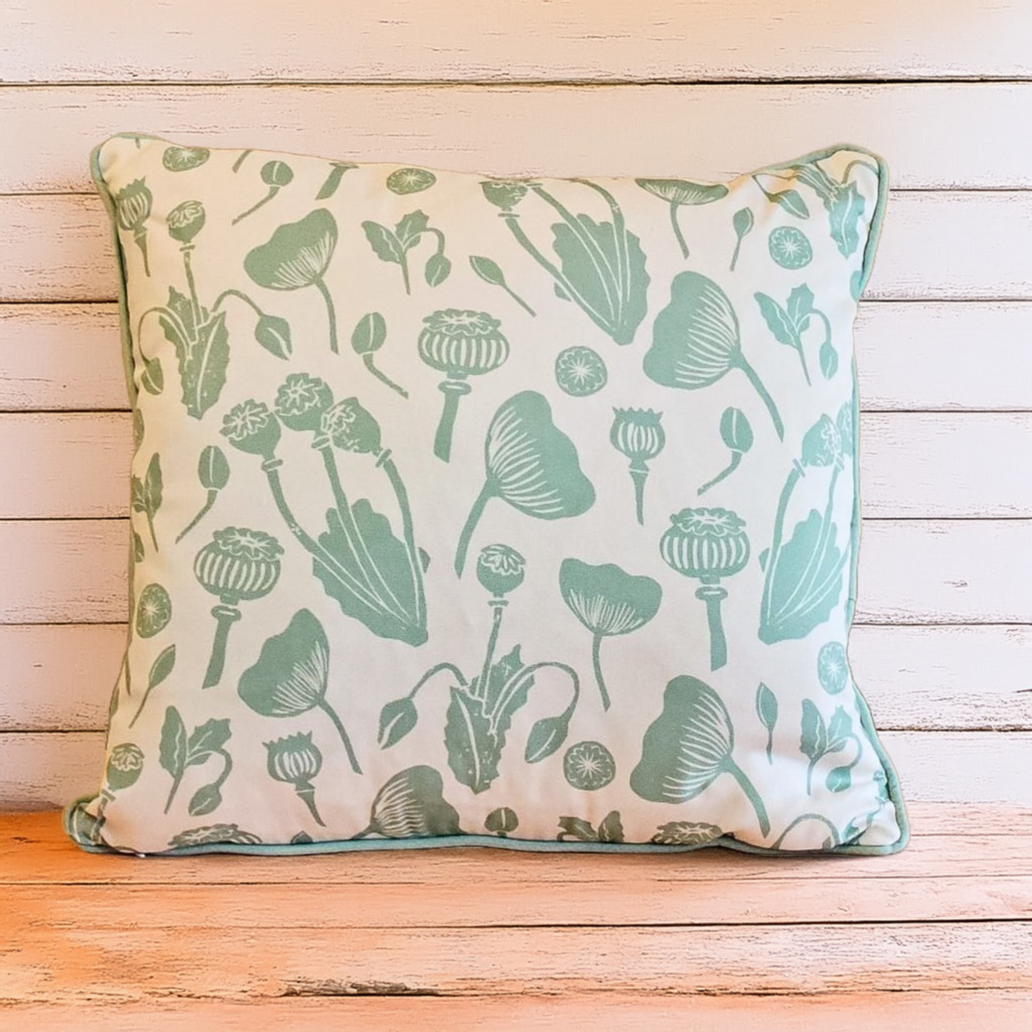 Decorative Zia Living Wild Poppies Print Cushion with green floral pattern on a neutral wooden background
