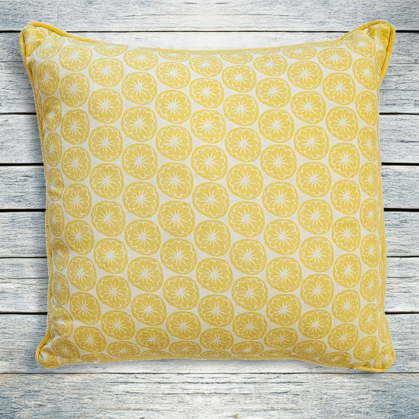 Yellow Seedhead patterned cushion, featuring bold circular yellow botanical motifs on a white background, on wooden surface — ZIA LIVING