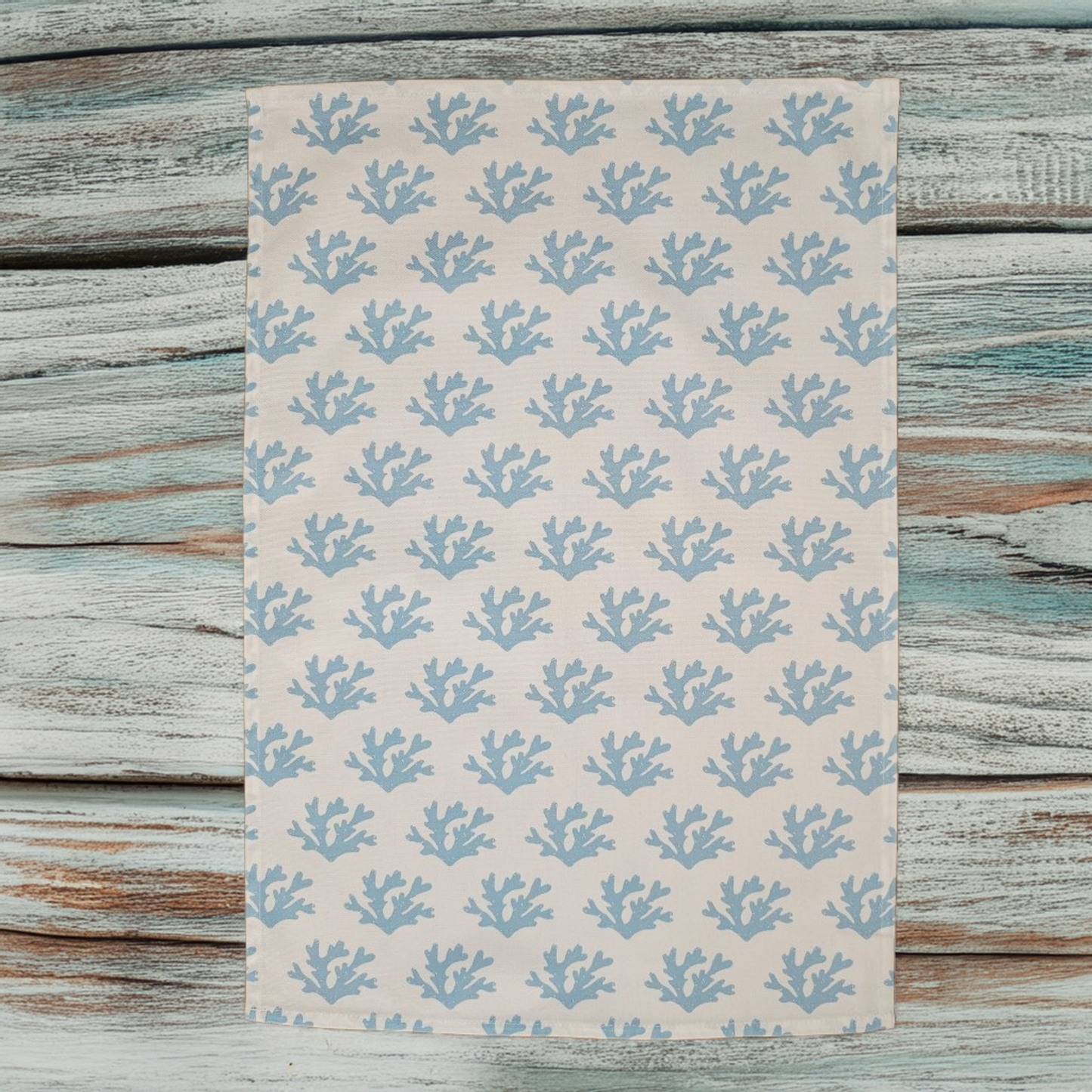 Sky Blue Seaweed patterned tea towel laid flat on a wooden surface, featuring flowing blue seaweed motifs on a light background — ZIA LIVING.