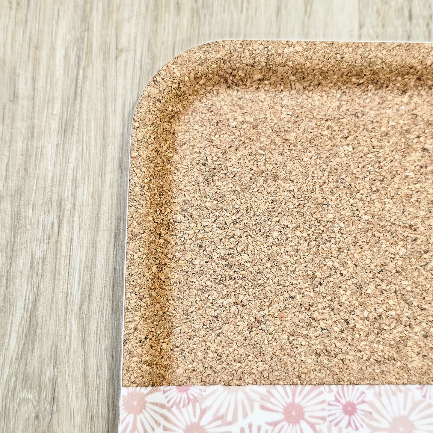 ZIA LIVING rectangular pink floral tray with close up of rounded cork area and corners displayed on a light wooden surface