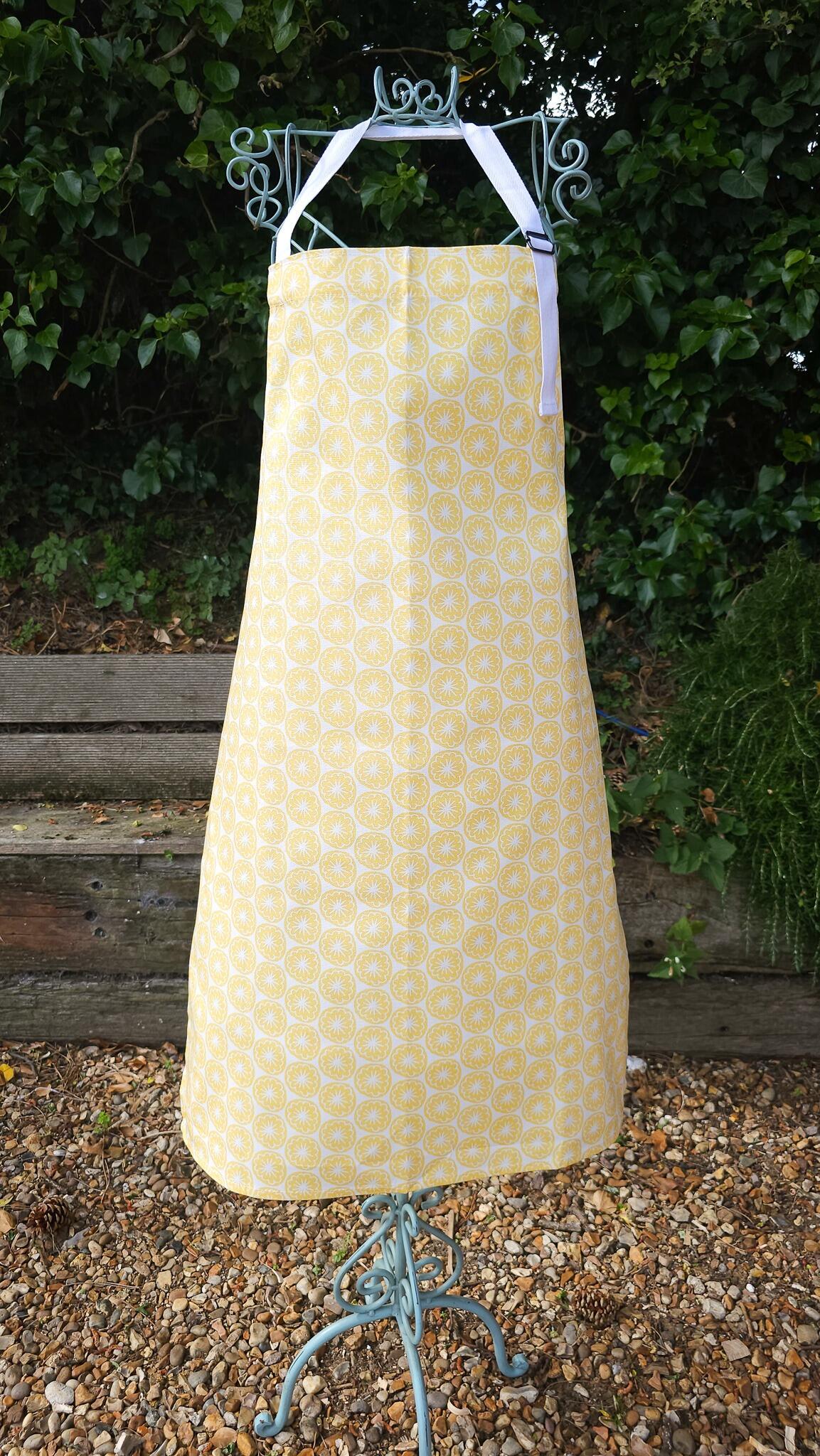 Yellow Seedhead apron featuring a yellow circular botanical motif, worn on a display outside — ZIA LIVING.