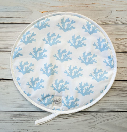Blue seaweed print Aga and hob covers by ZIA LIVING, featuring a white coral motif on a deep‑blue cotton base, shown on a glossy black stove with metal handles.