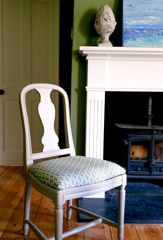 ZIA LIVING’s Anello cotton‑linen fabric in rosemary and white, showing its interlocking oval and diamond geometric weave pattern and textured artisan finish featured on a dining room chair. 