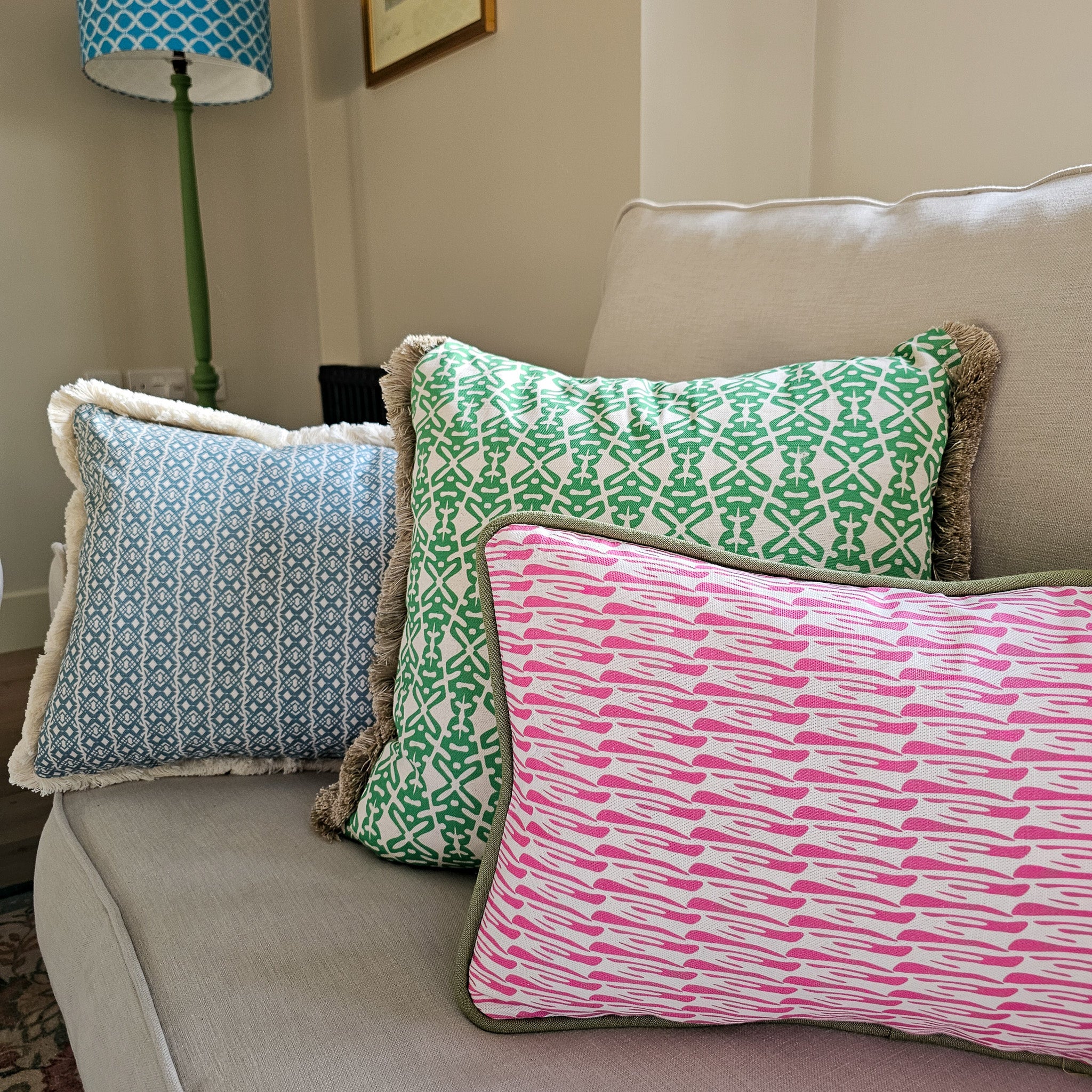 Three patterned pillows on a couch with a lamp in the background by Zia Living
