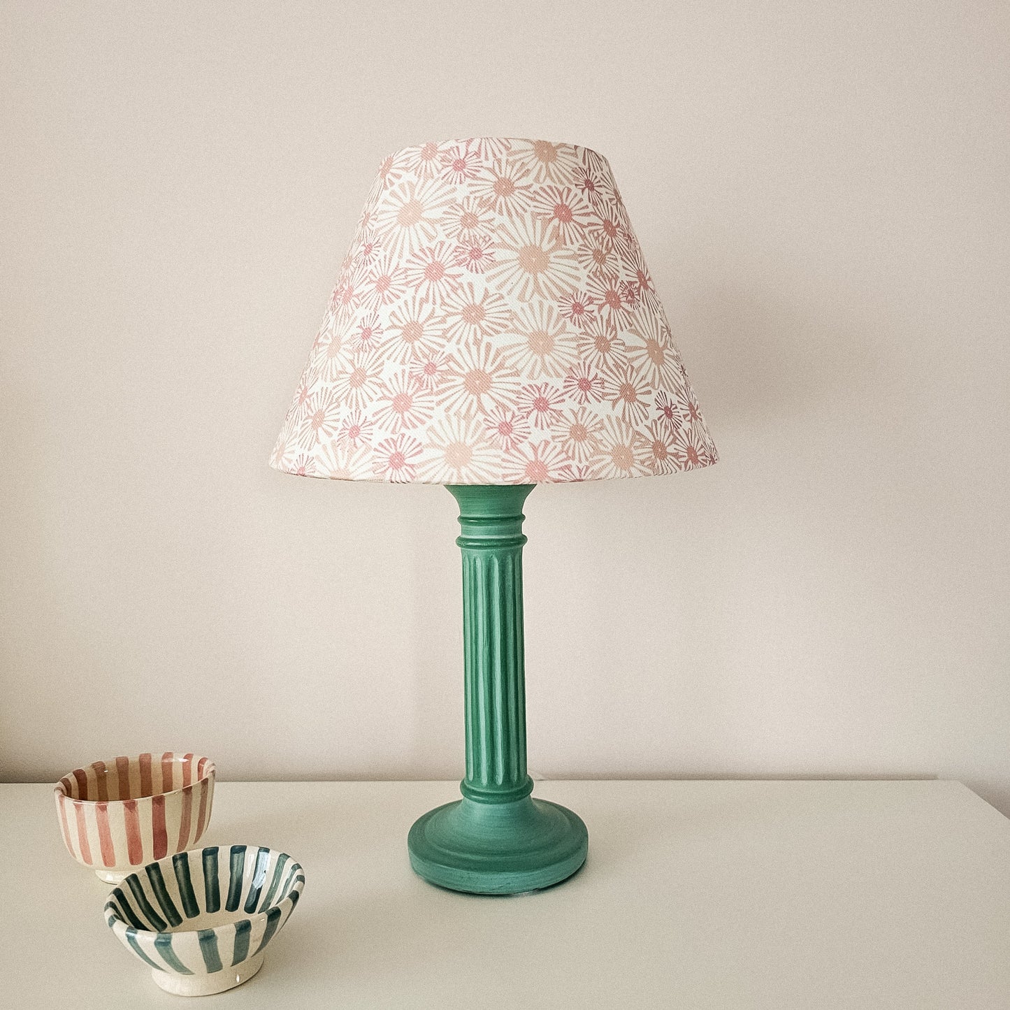 Conical lampshade in Pink Daisy floral fabric on a green lamp base, styled with striped ceramic bowls — artisan home décor by ZIA LIVING.