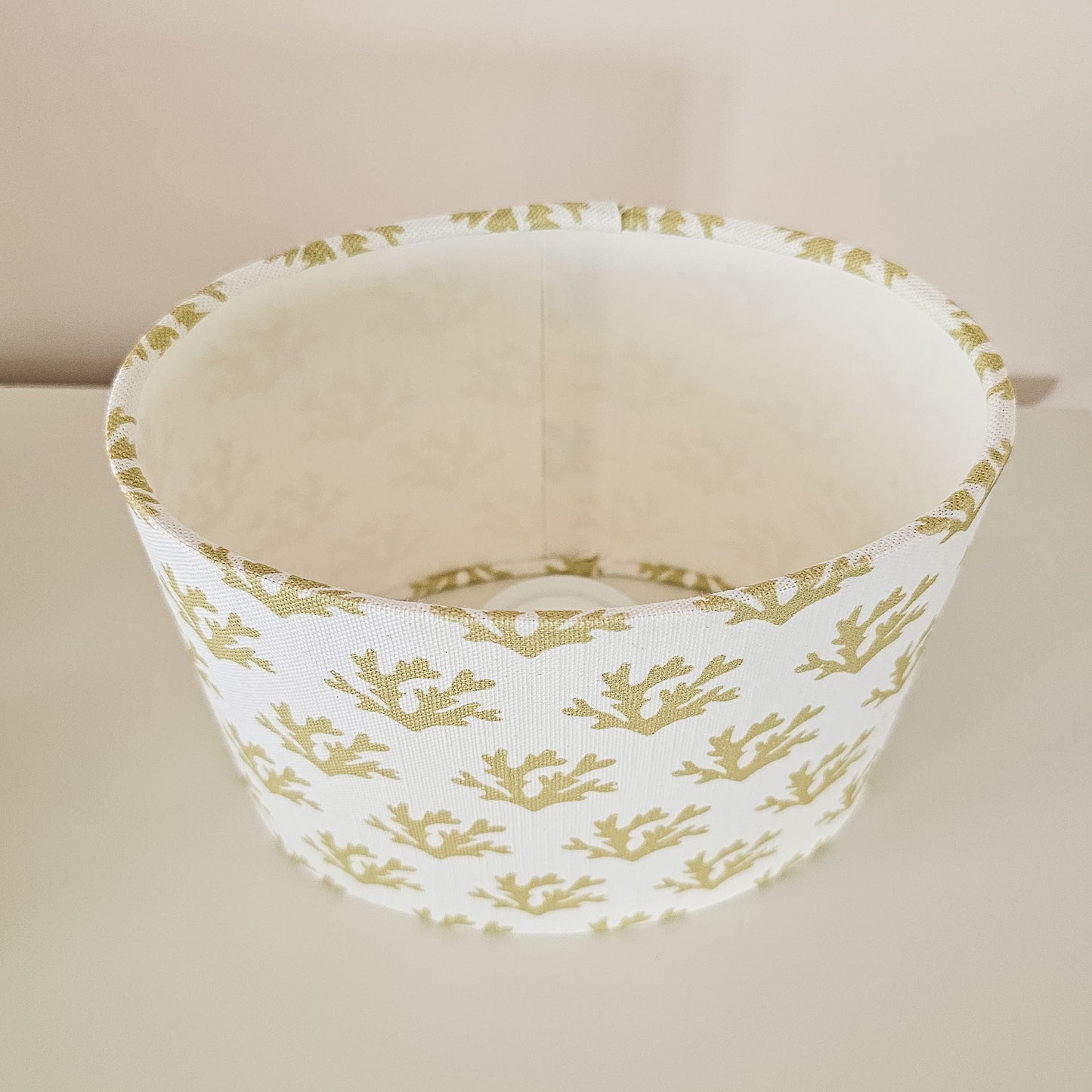Seaweed motif lampshade by ZIA LIVING, featuring a repeating sand coloured sea‑coral pattern on a white cotton‑linen oval shade. View of shape.