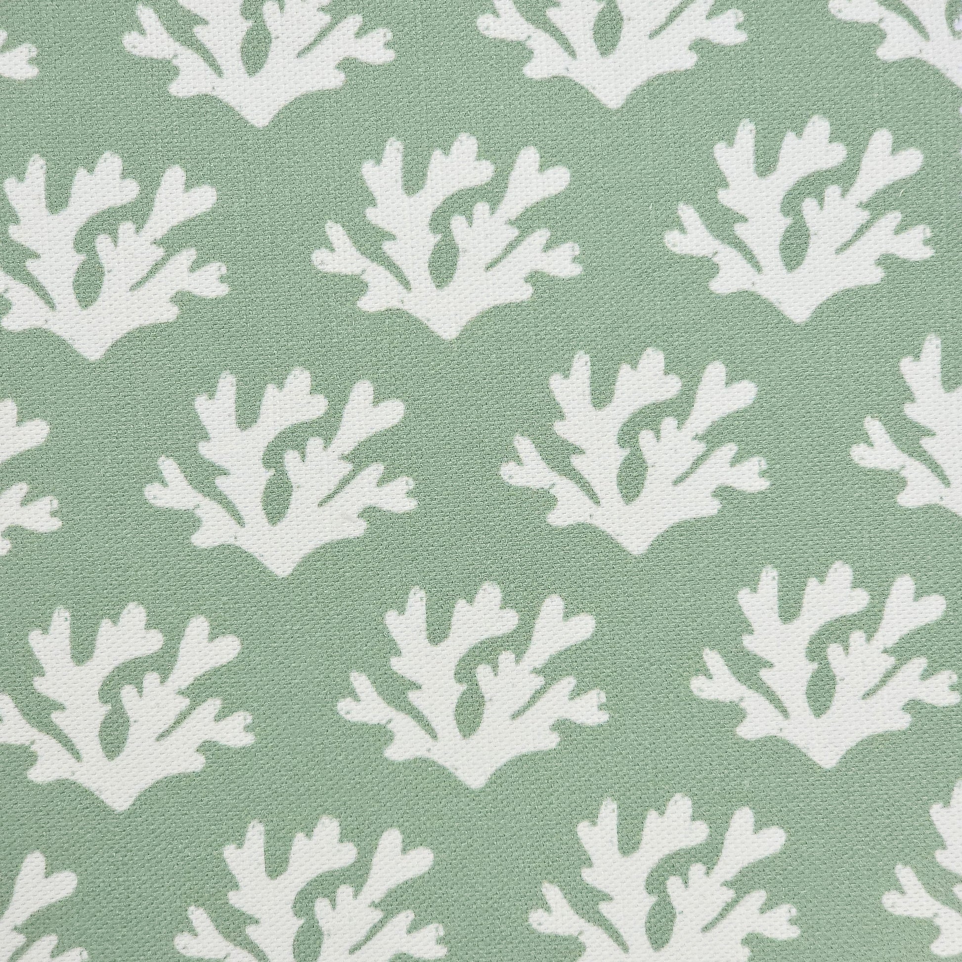 Seaweed cotton linen fabric featuring white lino print seaweed motifs in a repeating coastal pattern on a soft green background. ZIA LIVING.