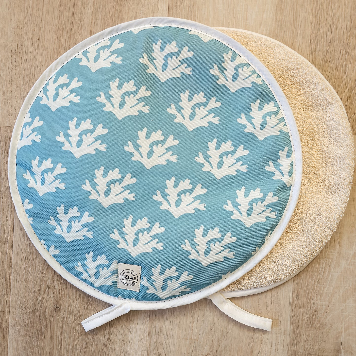 A pair of round Seaweed print aga hob cover  from ZIA LIVING arranged on a wooden surface showing front fully design and towelling reverse