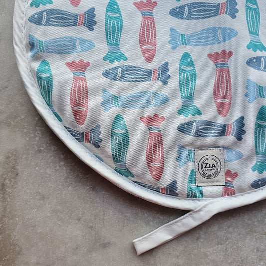 Fish print round kitchen cover by ZIA LIVING, featuring a repeating red, teal and light‑blue fish motif close up on marble worktop
