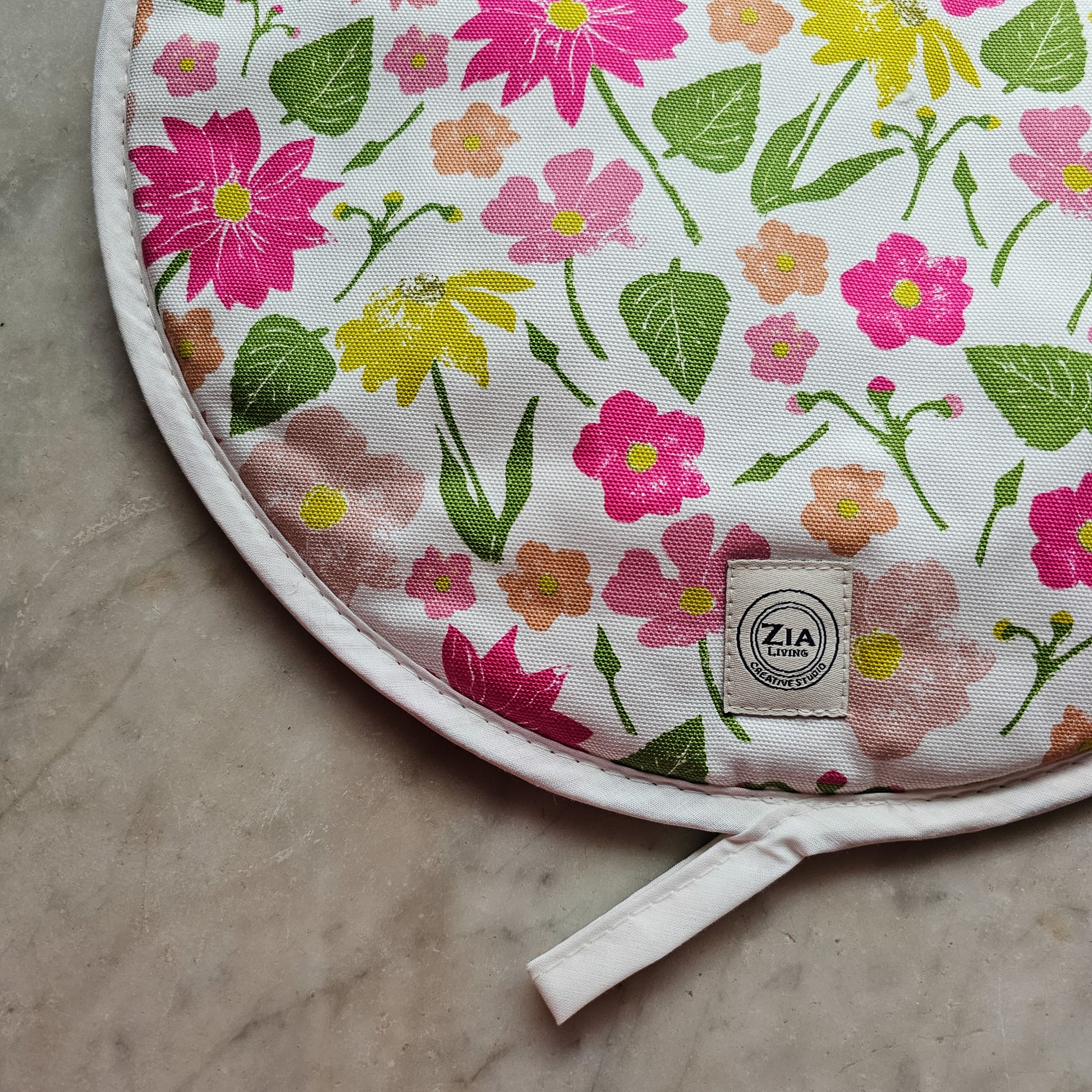 A Flower Garden print round aga hob cover close up from ZIA LIVING arranged on a white marble surface 