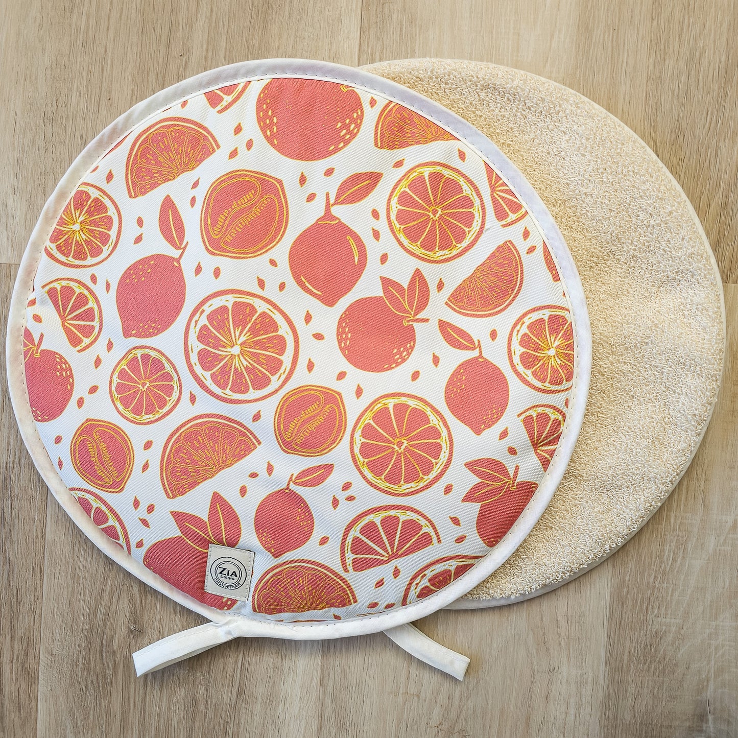 A pair of round Moro Orange aga hob covers ZIA LIVING arranged on a wooden worktop showing front design and towelling reverse