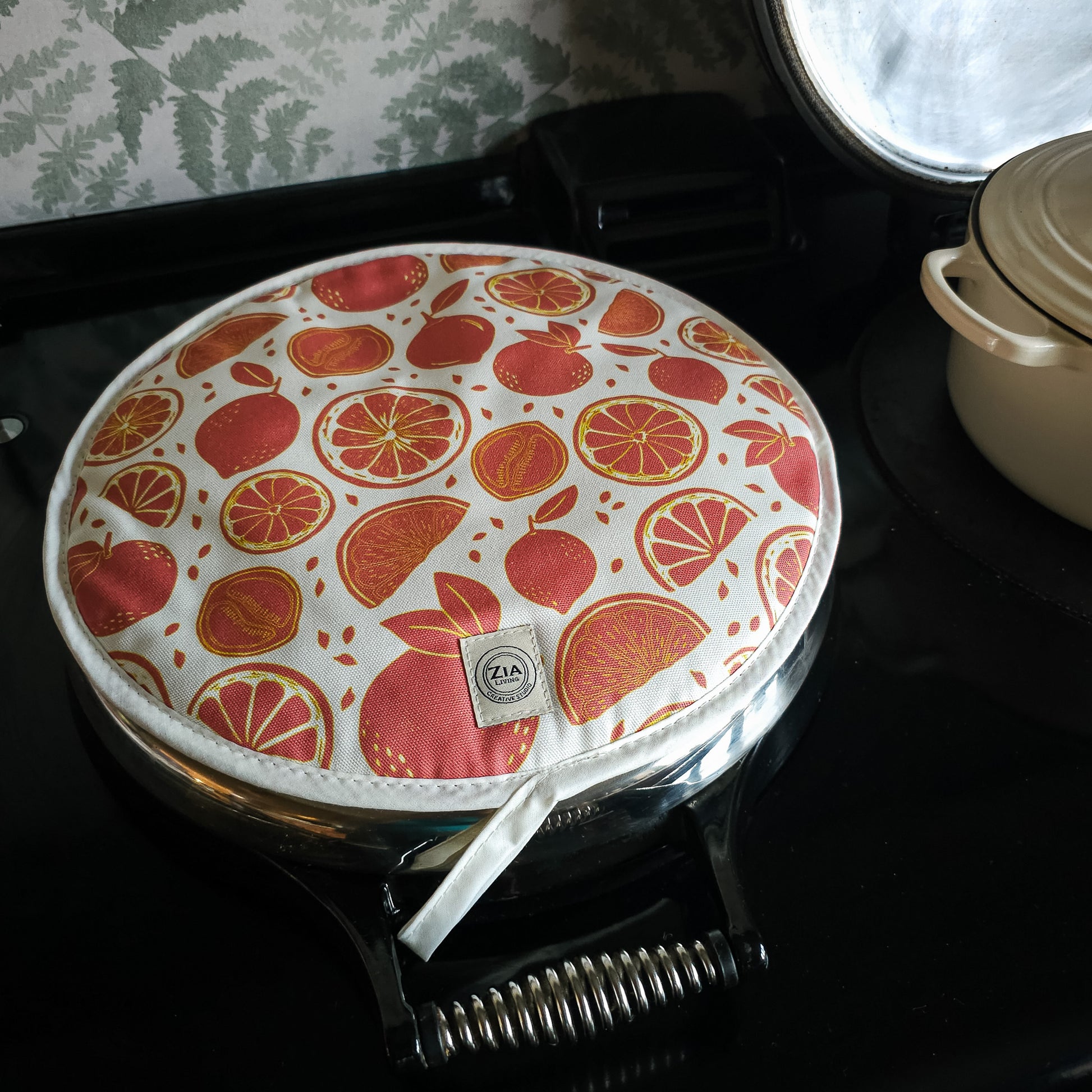 Citrus print round kitchen cover by ZIA LIVING, featuring orange and grapefruit motifs on a white cotton‑linen base, shown on aga top