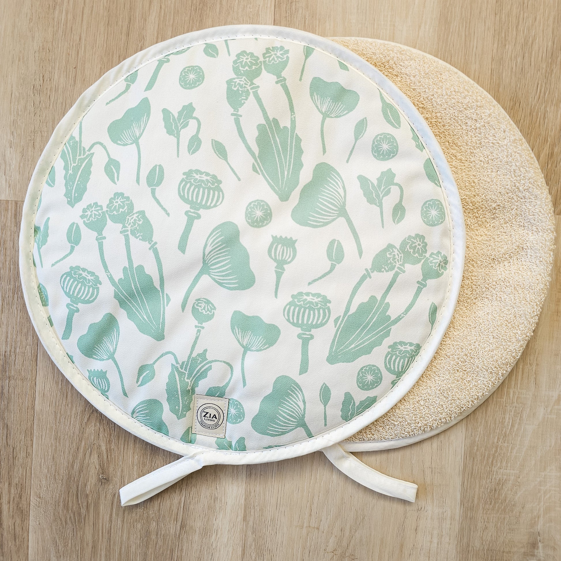 Green botanical print Aga and hob covers by ZIA LIVING, featuring a cream cotton‑linen base with stylised green floral motifs, shown on a front and towelling reverse.