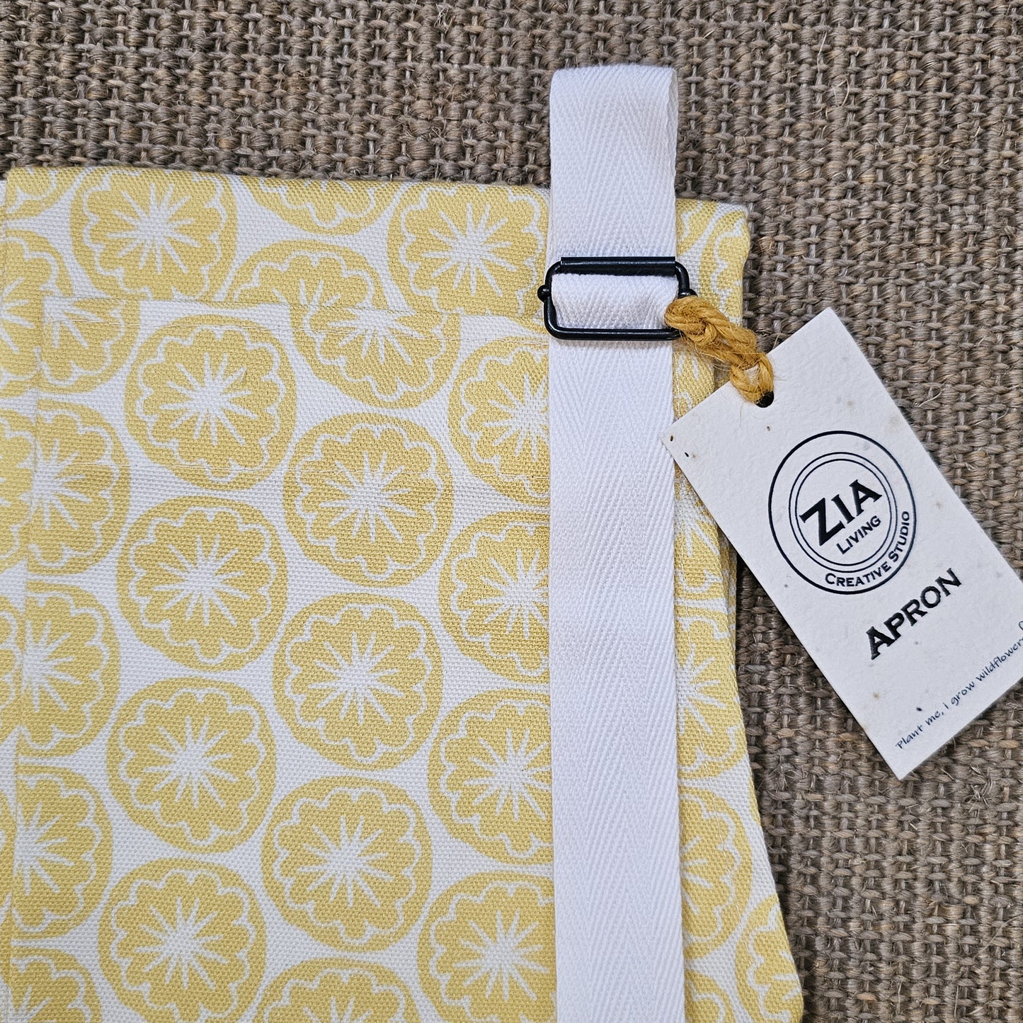 Yellow Seedhead apron featuring a yellow circular botanical motif, close up, with buckle and strap— ZIA LIVING.