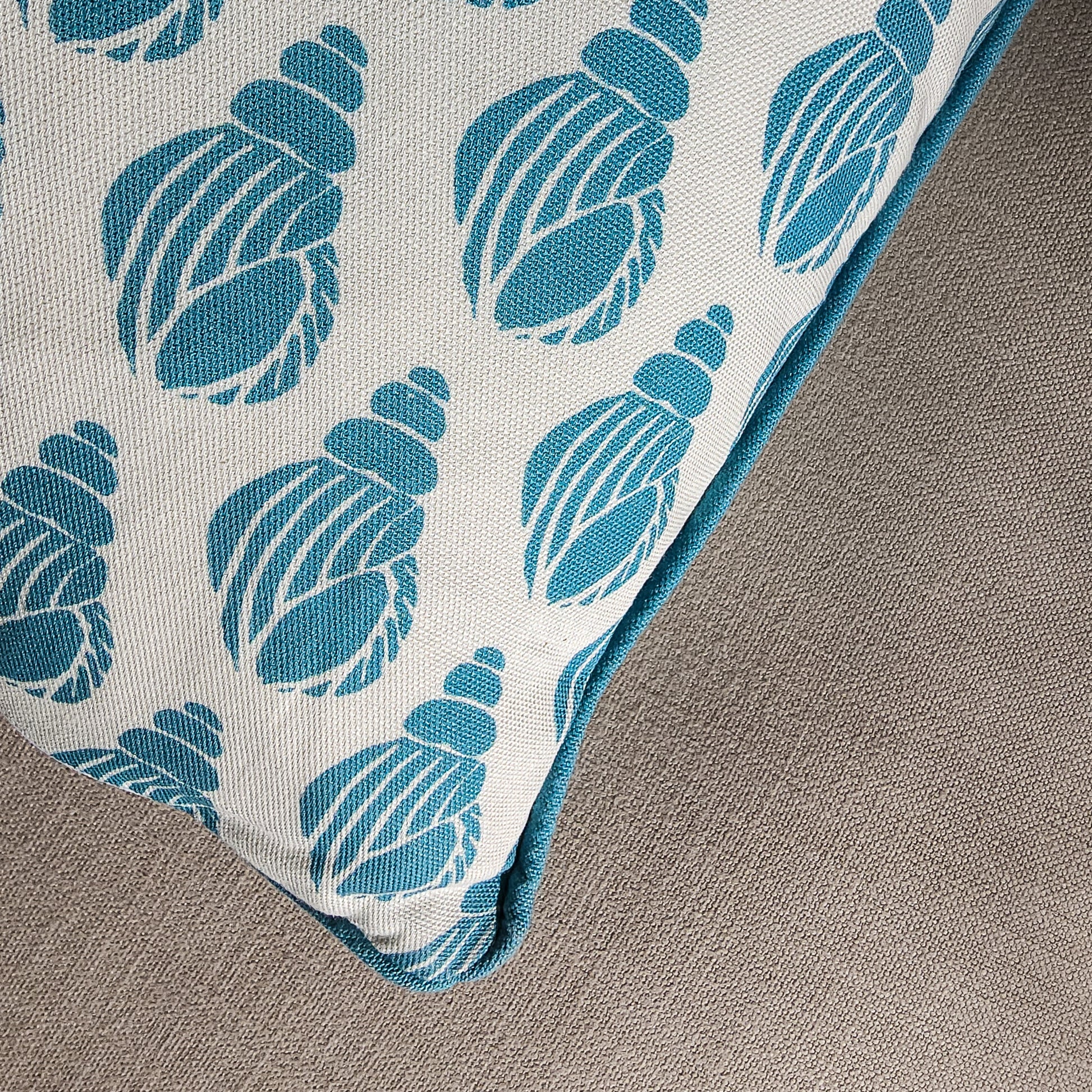 Sea Blue Shell cushion featuring a repeating hand‑carved shell motif in blue on a white background, photographed close -up— ZIA LIVING.