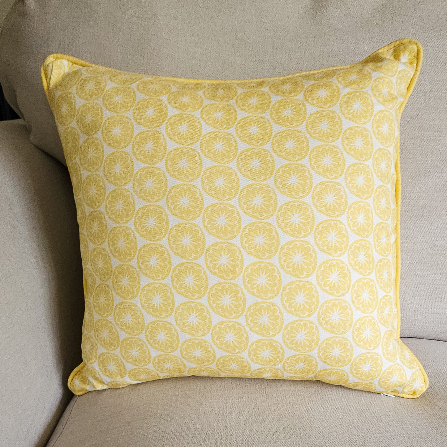 Yellow Seedhead patterned cushion, featuring bold circular yellow botanical motifs on a white background, placed on sofa — ZIA LIVING