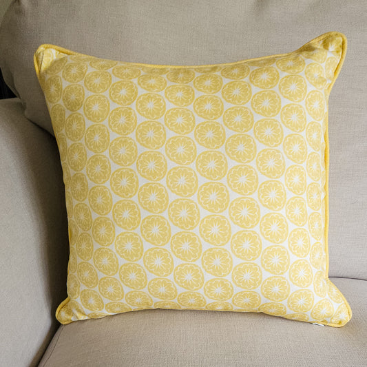 Yellow Seedhead patterned cushion, featuring bold circular yellow botanical motifs on a white background, placed on sofa — ZIA LIVING