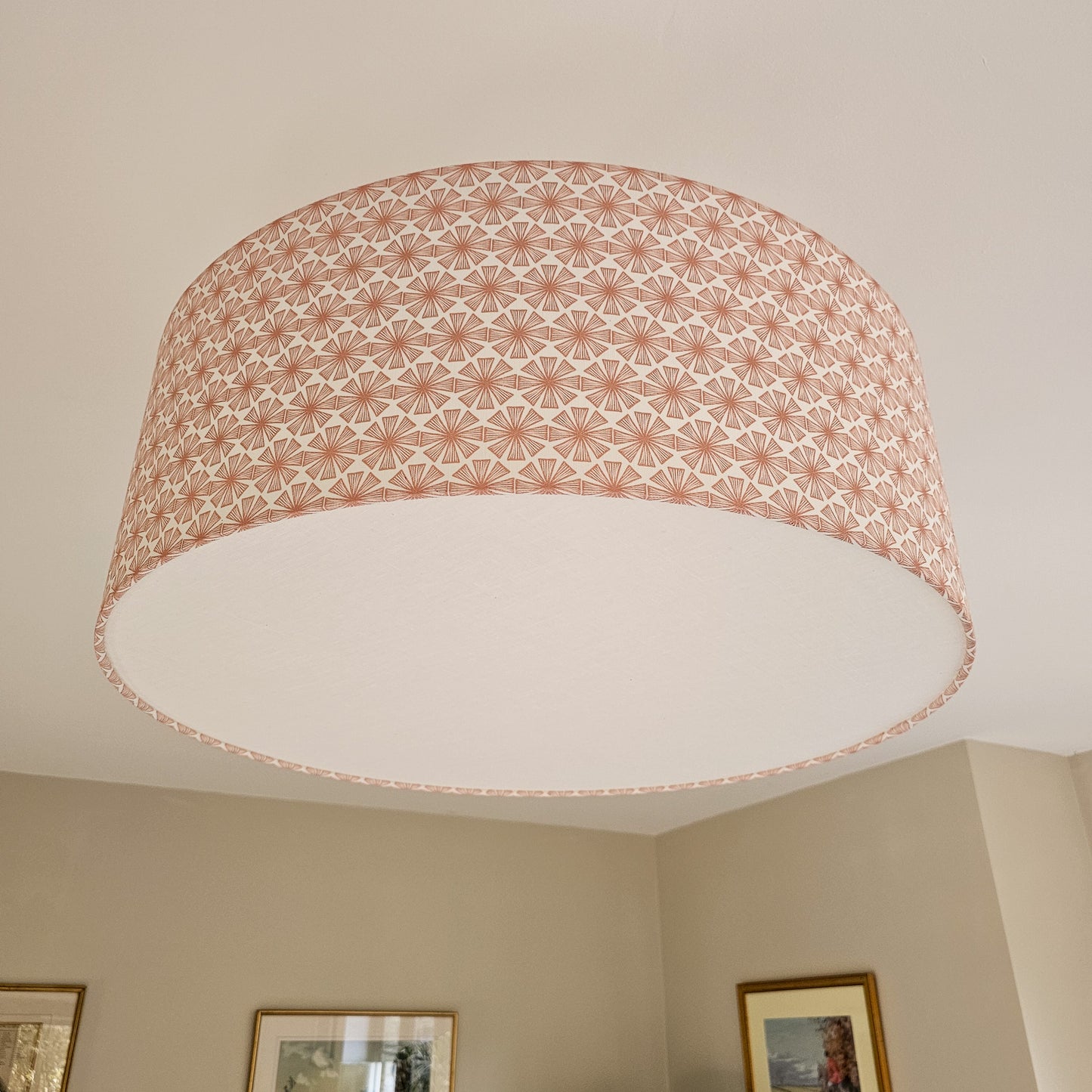Ceiling shade in Stella pattern from Zia Living in Peach and White with diffuser with framed pictures on the wall.