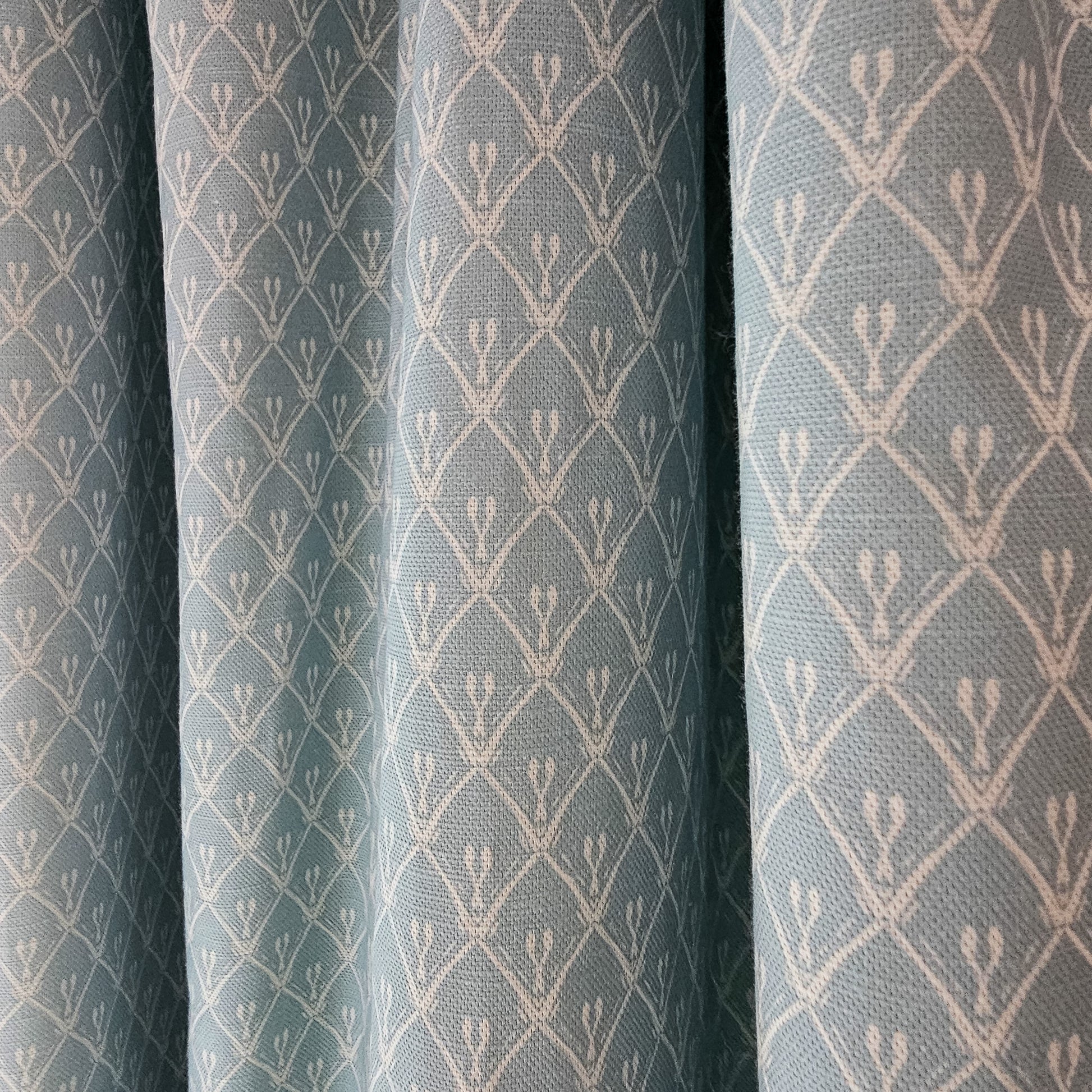Blue trellis‑style lino print on cotton‑linen fabric with a natural textured background, featured as curtains— ZIA LIVING.