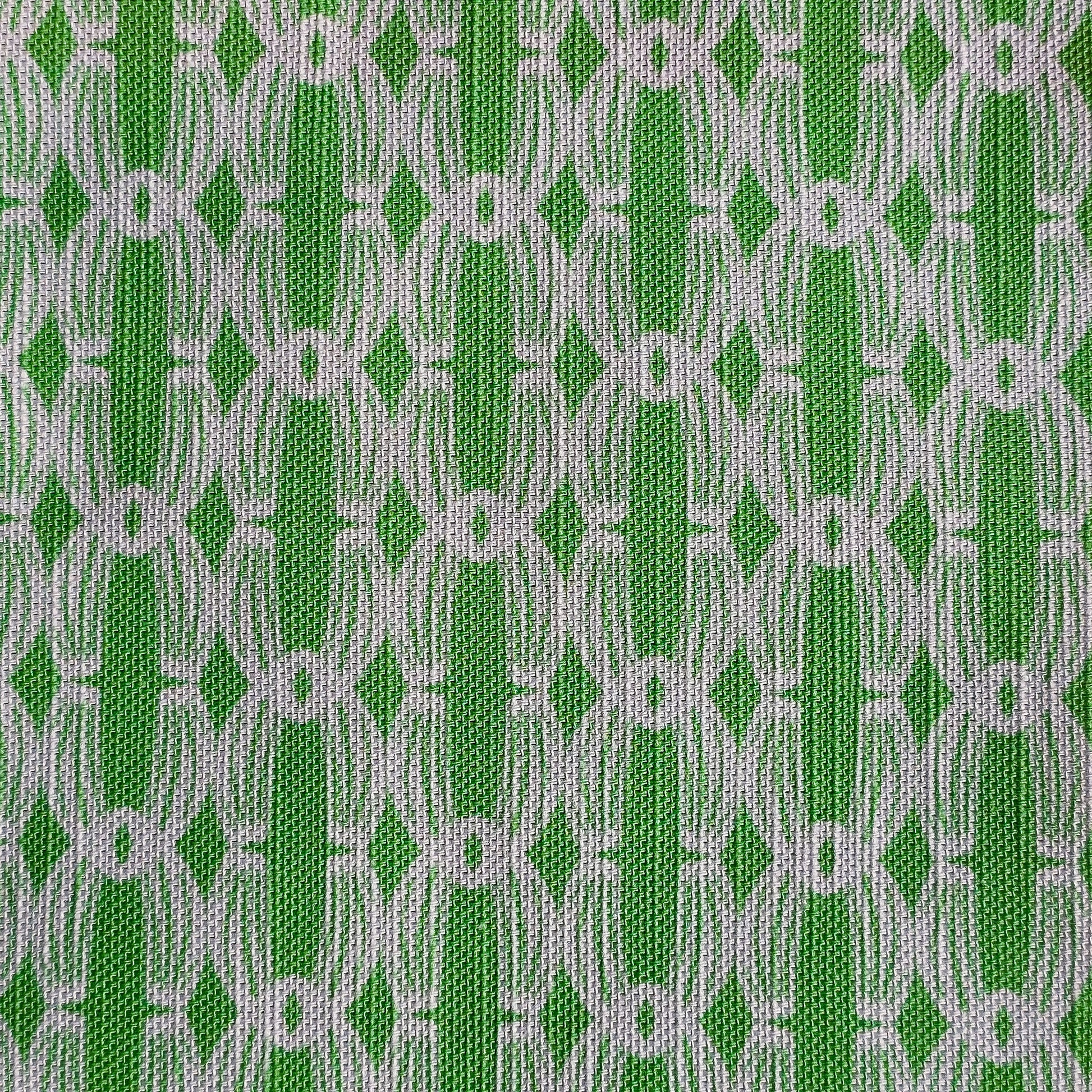 Close‑up of ZIA LIVING’s Anello cotton‑linen fabric in apple green and white, showing its interlocking oval and diamond geometric weave pattern and textured artisan finish.