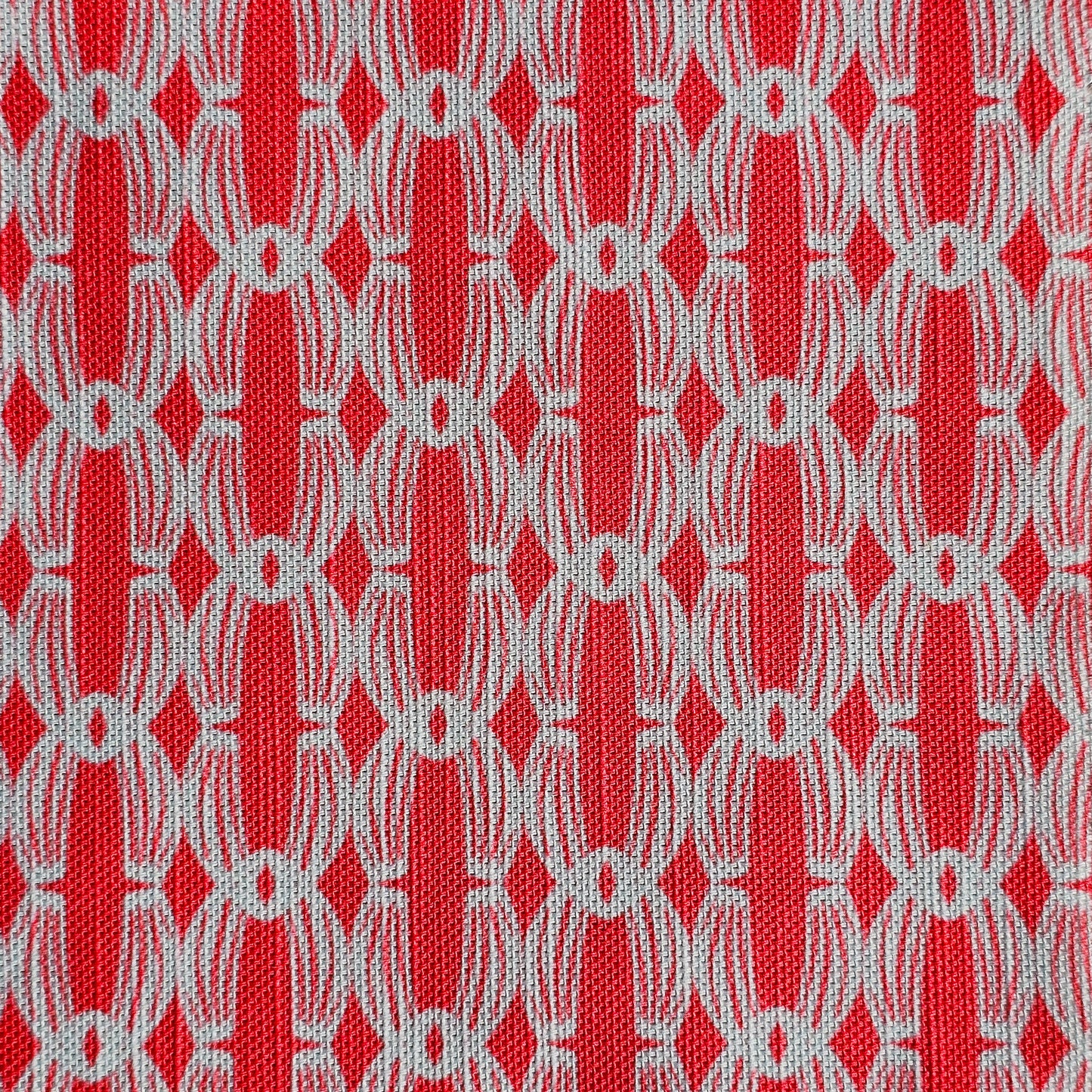 Close‑up of ZIA LIVING’s Anello cotton‑linen fabric in rose and white, showing its interlocking oval and diamond geometric weave pattern and textured artisan finish.