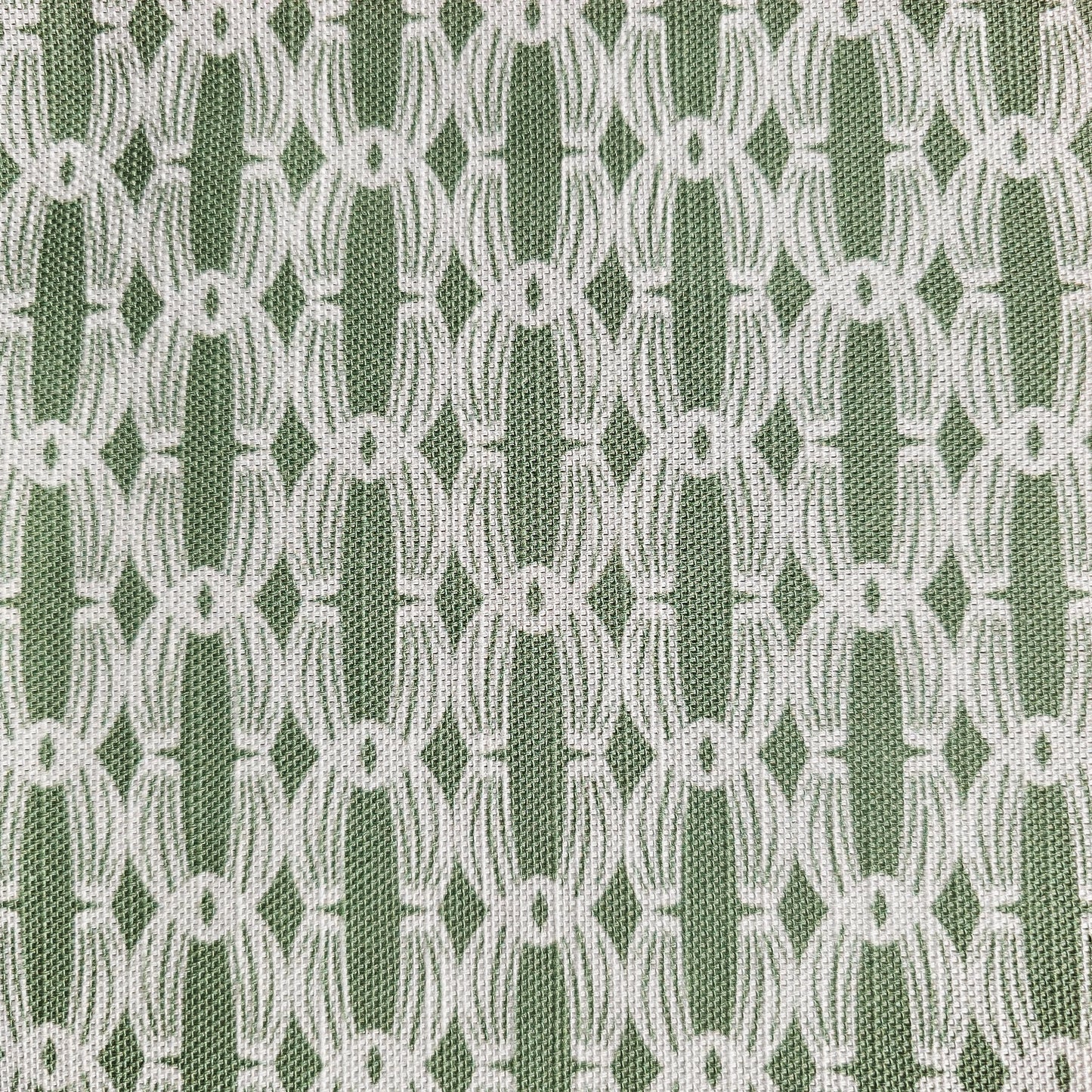 Close‑up of ZIA LIVING’s Anello cotton‑linen fabric in rosemary green and white, showing its interlocking oval and diamond geometric weave pattern and textured artisan finish.