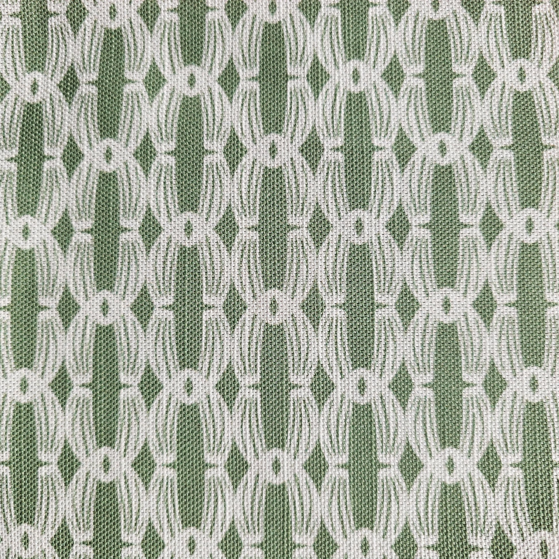 Close‑up of ZIA LIVING’s Anello cotton‑linen fabric in rosemary green and white, showing its interlocking oval and diamond geometric weave pattern and textured artisan finish.