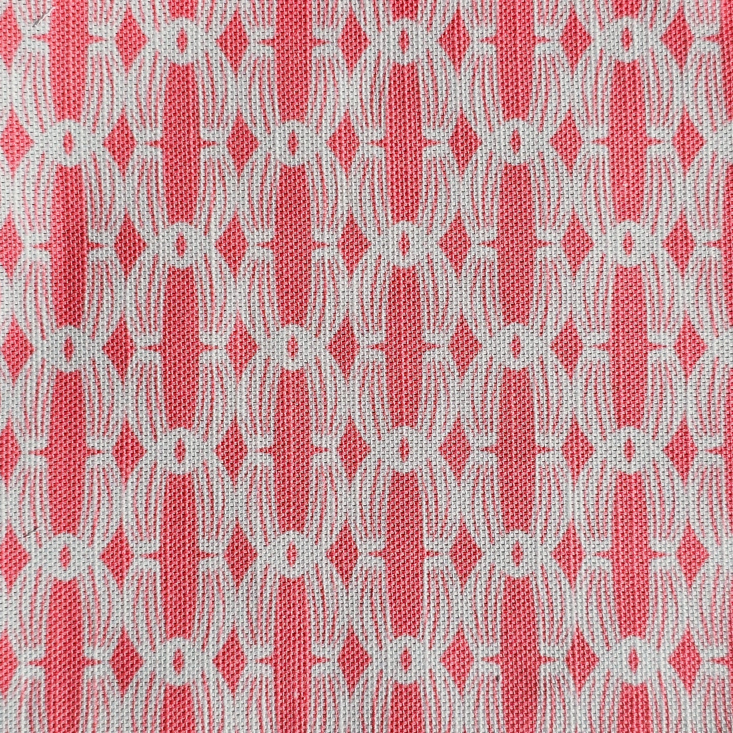 Close‑up of ZIA LIVING’s Anello cotton‑linen fabric in zinnia and white, showing its interlocking oval and diamond geometric weave pattern and textured artisan finish.