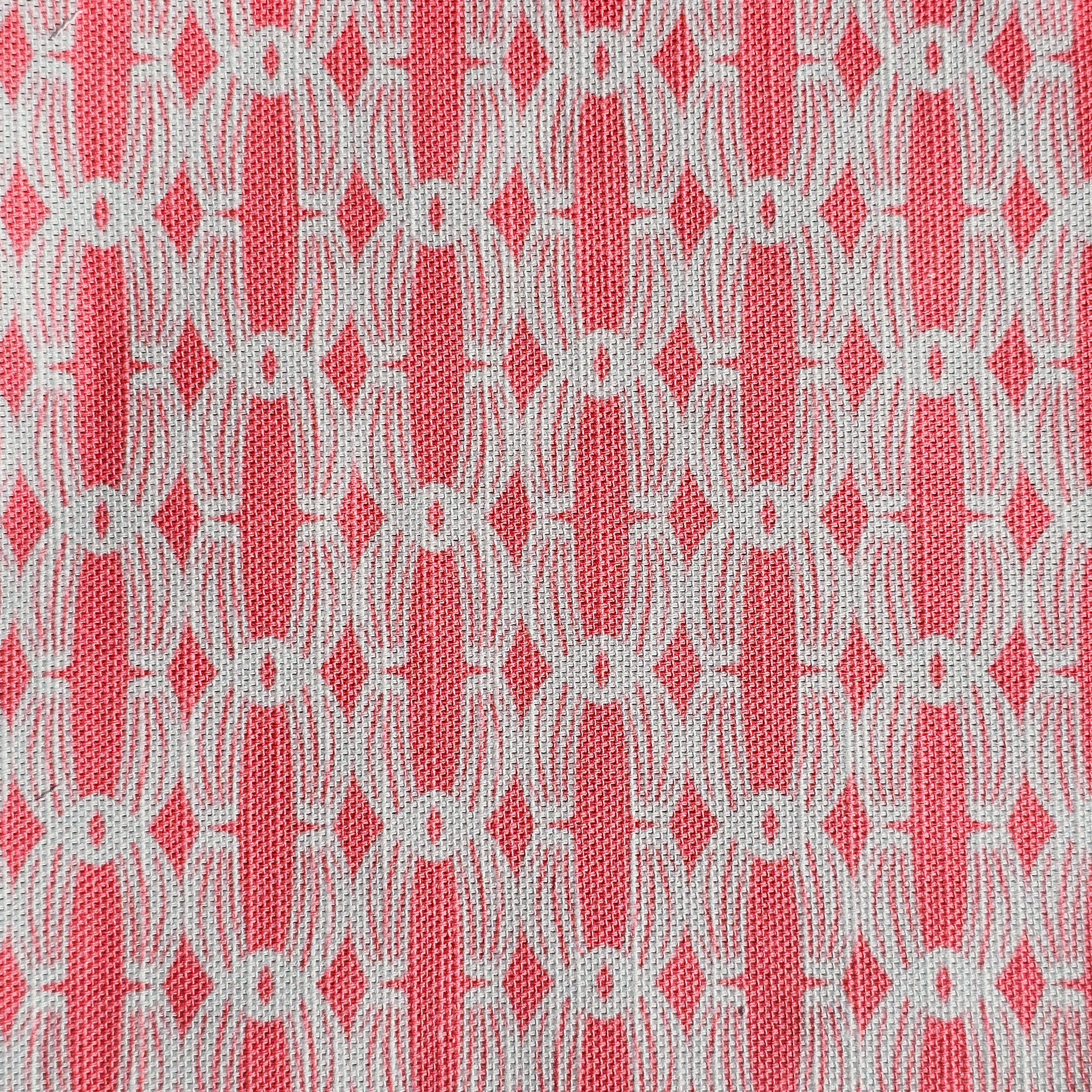 Close‑up of ZIA LIVING’s Anello cotton‑linen fabric in zinnia and white, showing its interlocking oval and diamond geometric weave pattern and textured artisan finish.