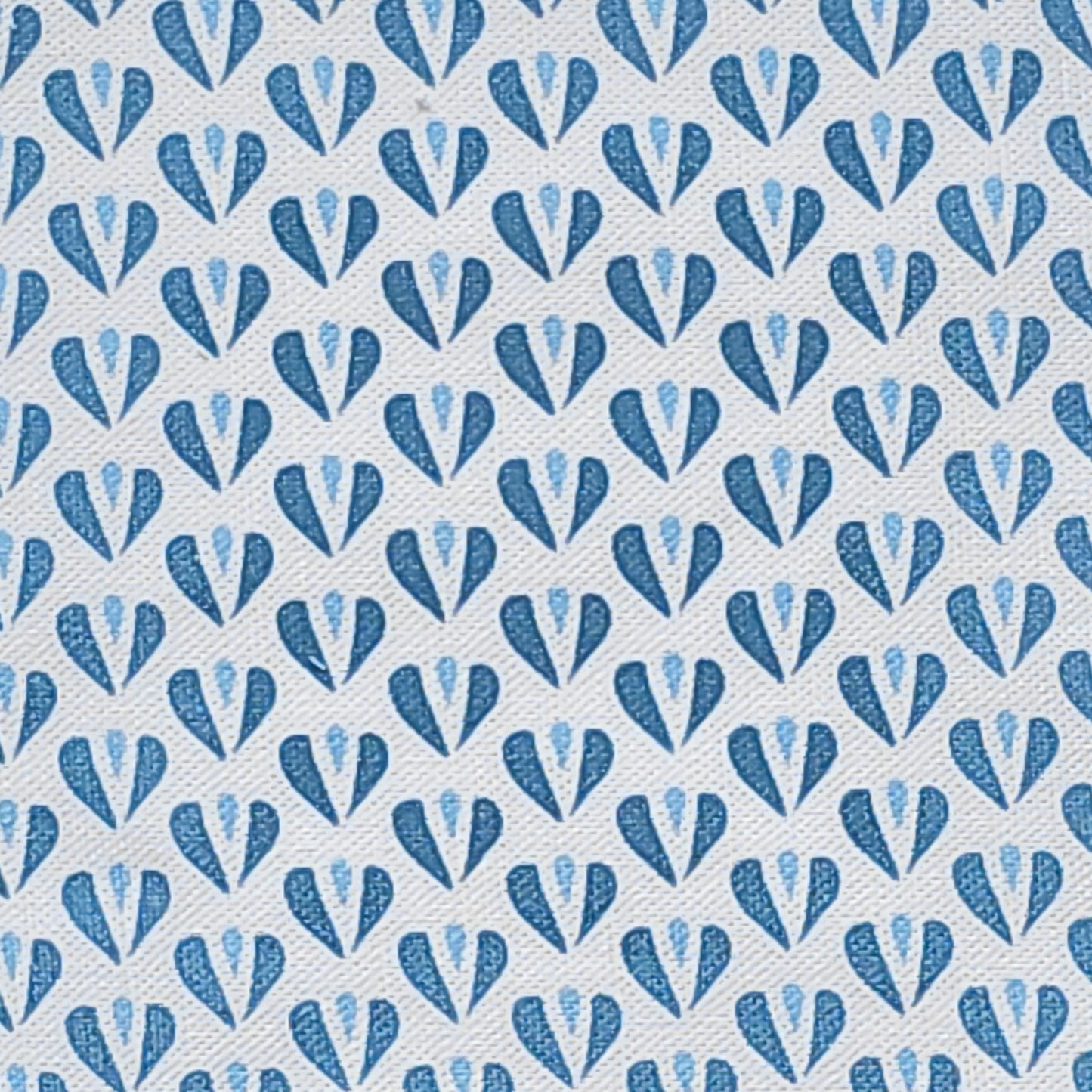 Carina, a heart motif patterned fabric by ZIA LIVING, featuring repeating blue and sky blue stylised heart shapes on a white textured cotton‑linen background.