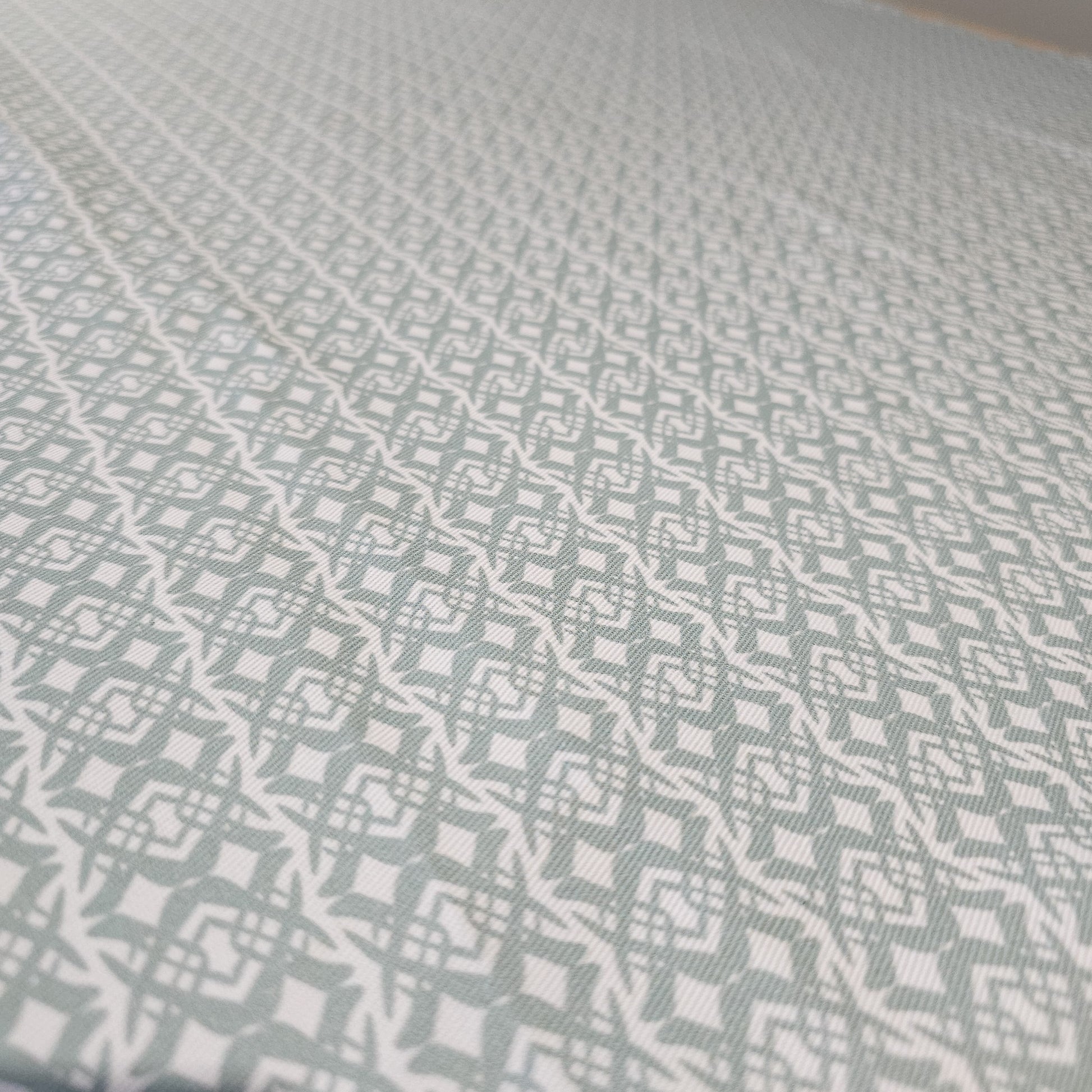 Fornet Classic cotton linen fabric close up featuring a repeating pale blue interlocking curved motif on an off‑white background. ZIA LIVING