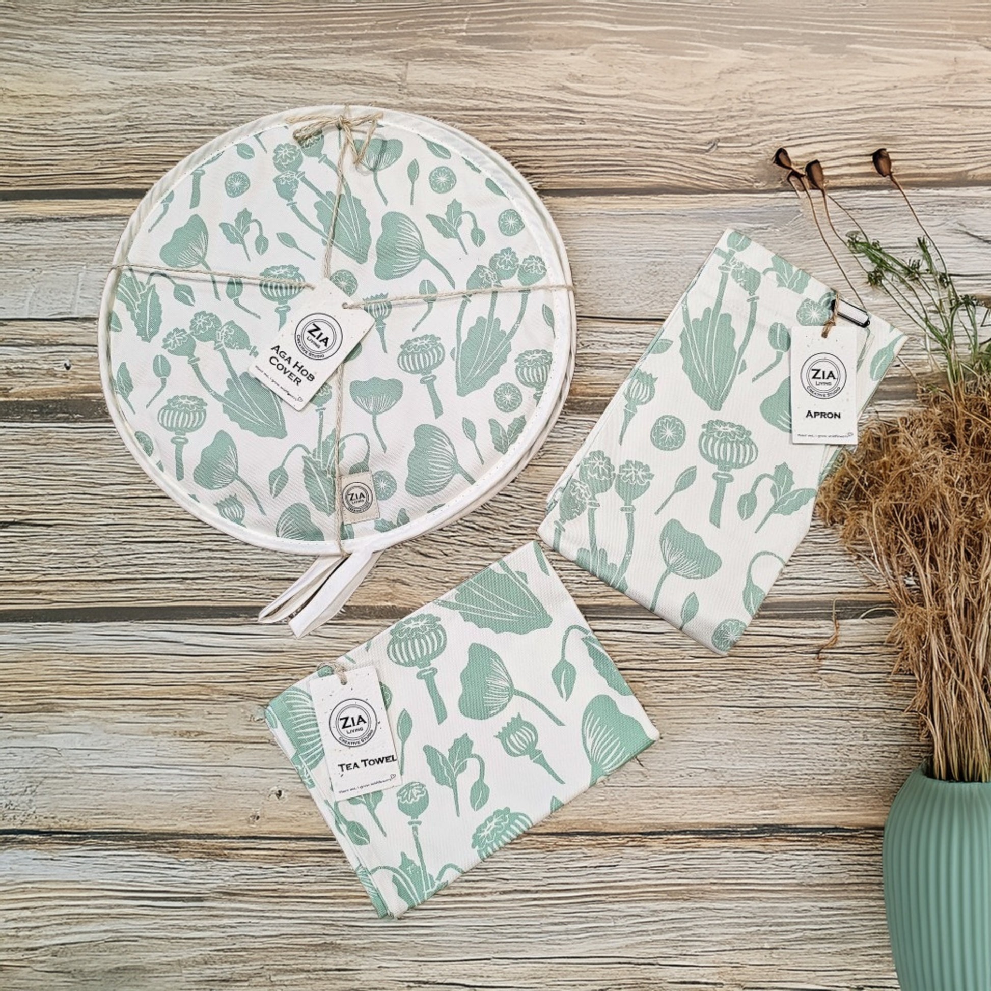 Set of green and white poppy print patterned kitchen linen set on a wooden surface with dried flowers by ZIA-Living.