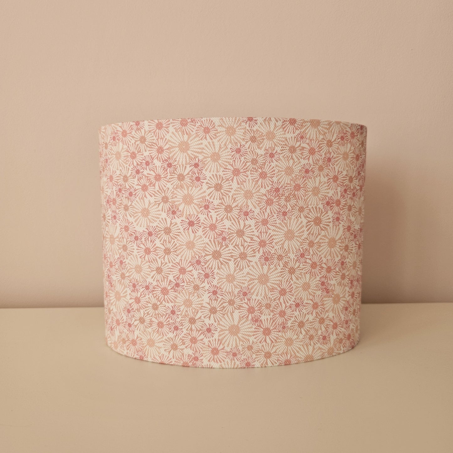 An oval lampshade in a pink Daisy print floral print fabric front view, against a neutral background.