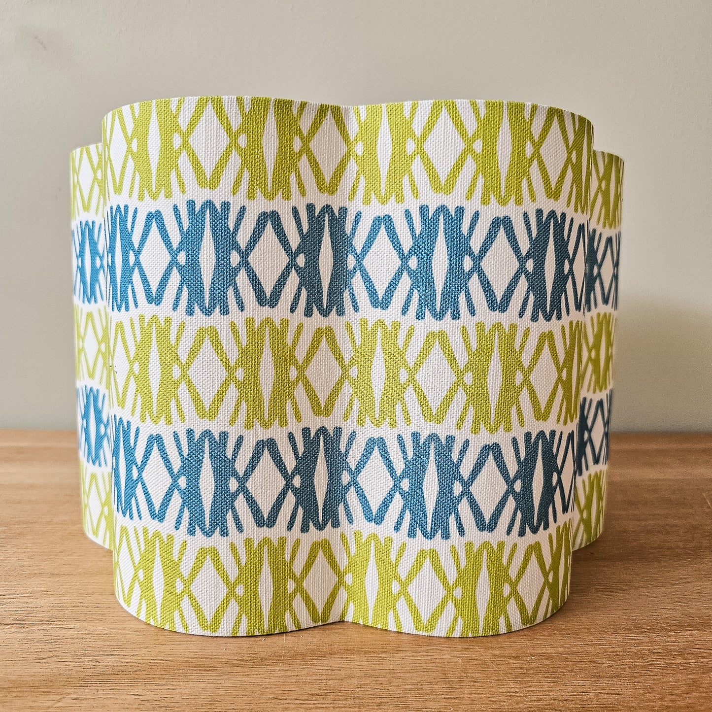 Seagrass print scalloped lampshade by ZIA LIVING, featuring a blue and green geometric lino‑print pattern on a white cotton‑linen shade with a wavy scalloped edge. Front view