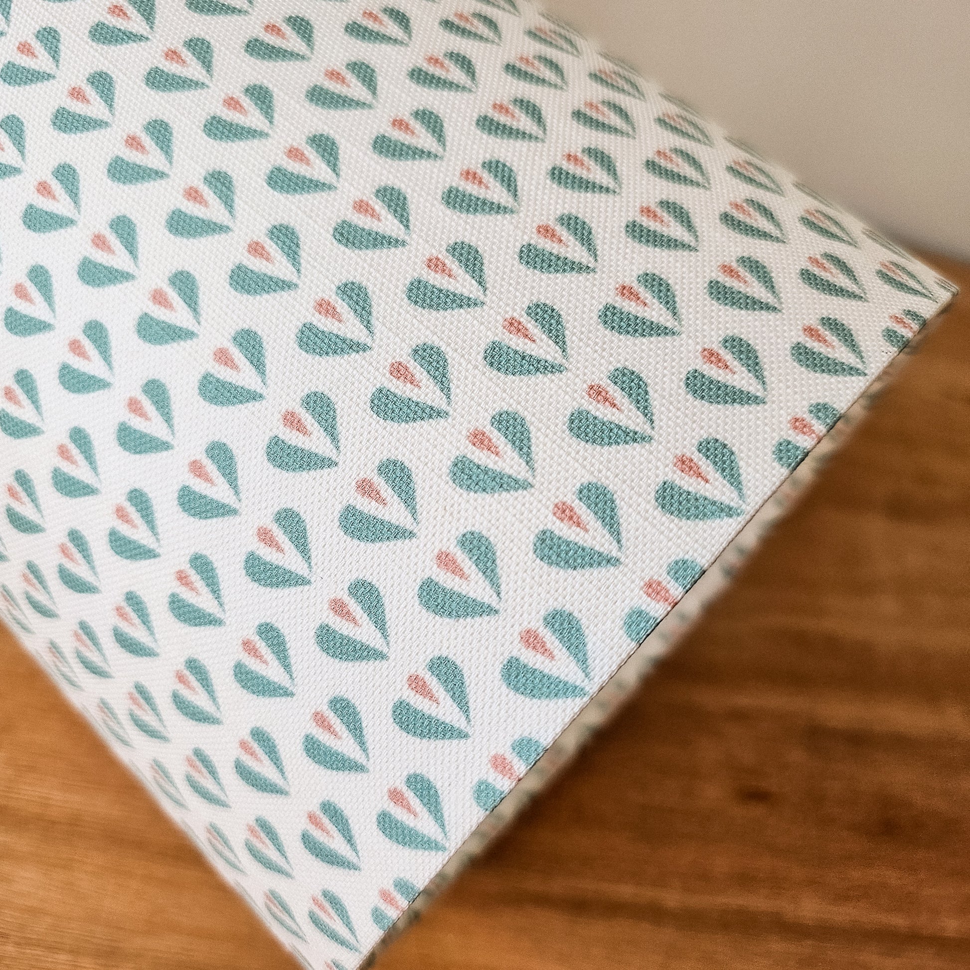Heart motif lampshade by ZIA LIVING, featuring a repeating teal and pink pattern on a light cotton‑linen shade, close up