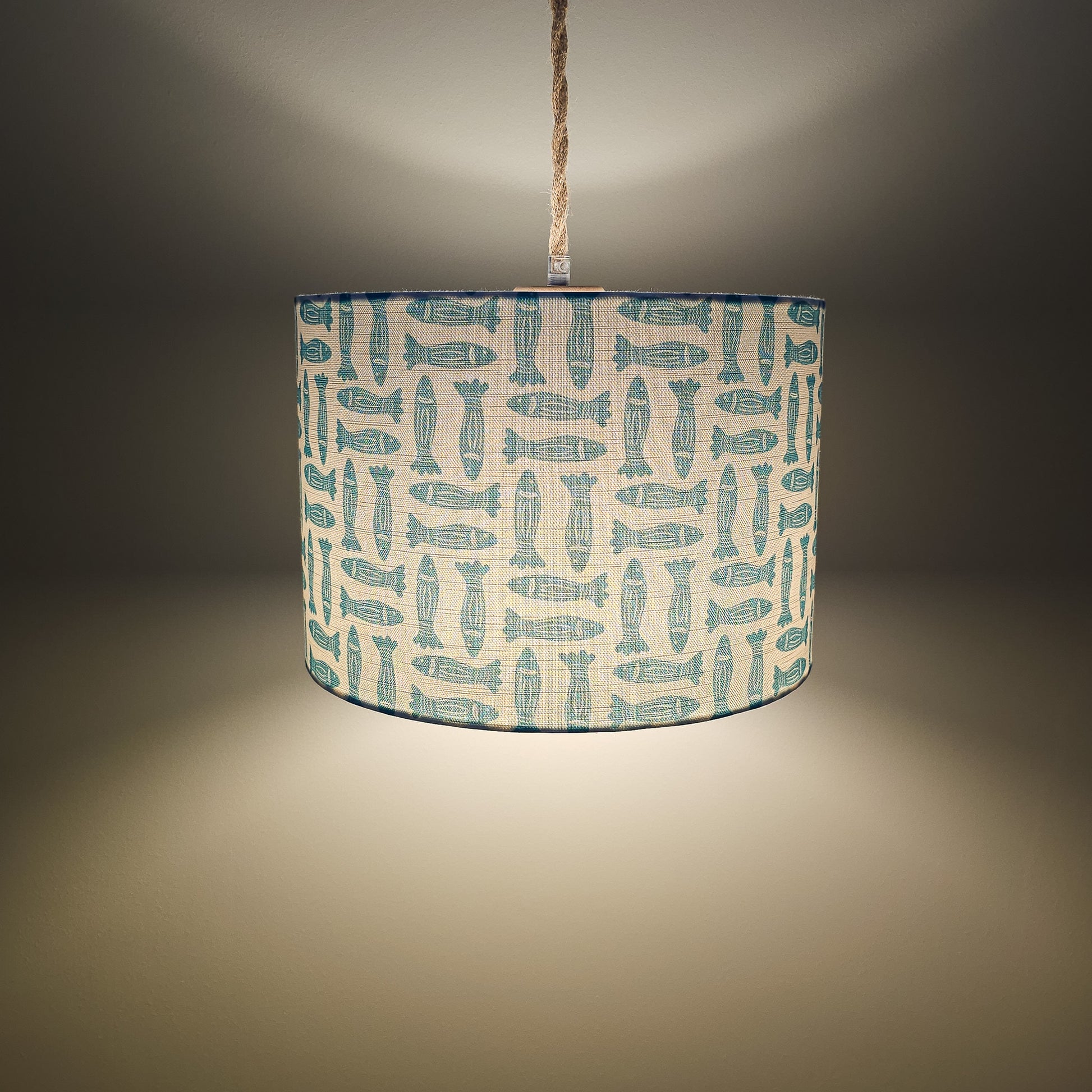 teal Fishes classic drum lampshade featuring simple hand‑drawn fish motifs on a warm neutral background, styled on a wooden surface — ZIA LIVING
