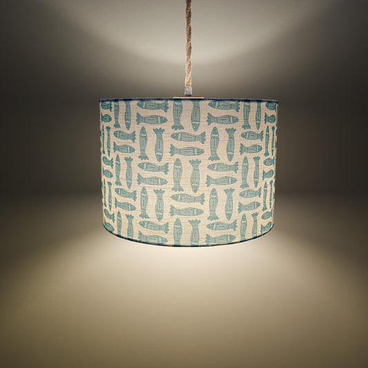 teal Fishes classic drum lampshade featuring simple hand‑drawn fish motifs on a warm neutral background, styled on a wooden surface — ZIA LIVING