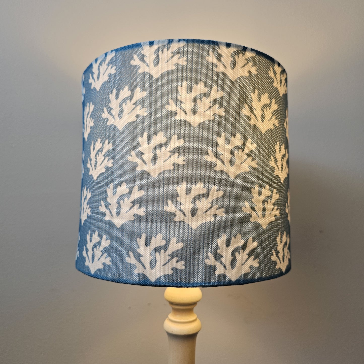 Zia Living Seaweed drum lampshade with white seaweed coral pattern on a blue background, cosy lamp on