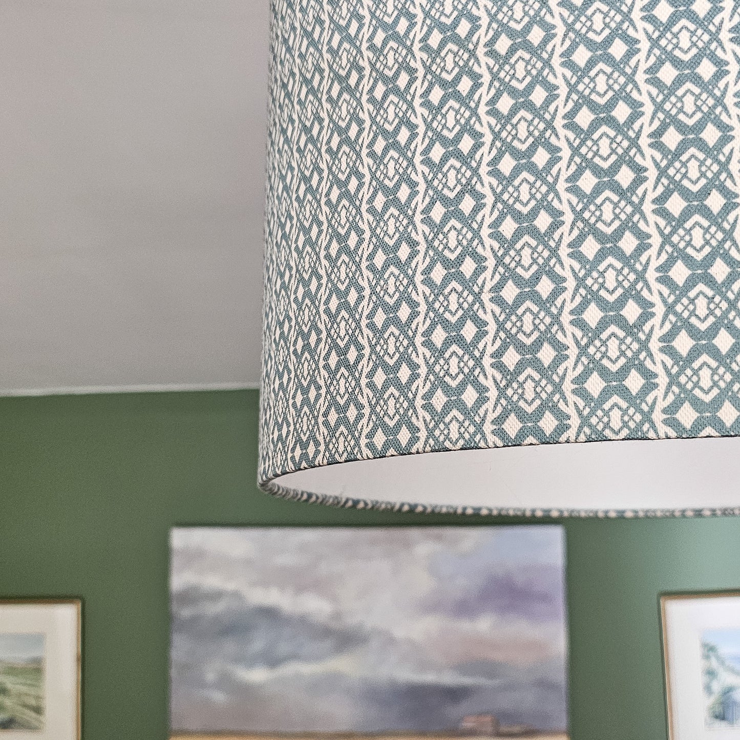 Fornet Classic cotton linen fabric swatch with a repeating blue interlocking curved motif on an off‑white background, featured on a ceiling lampshade. ZIA LIVING