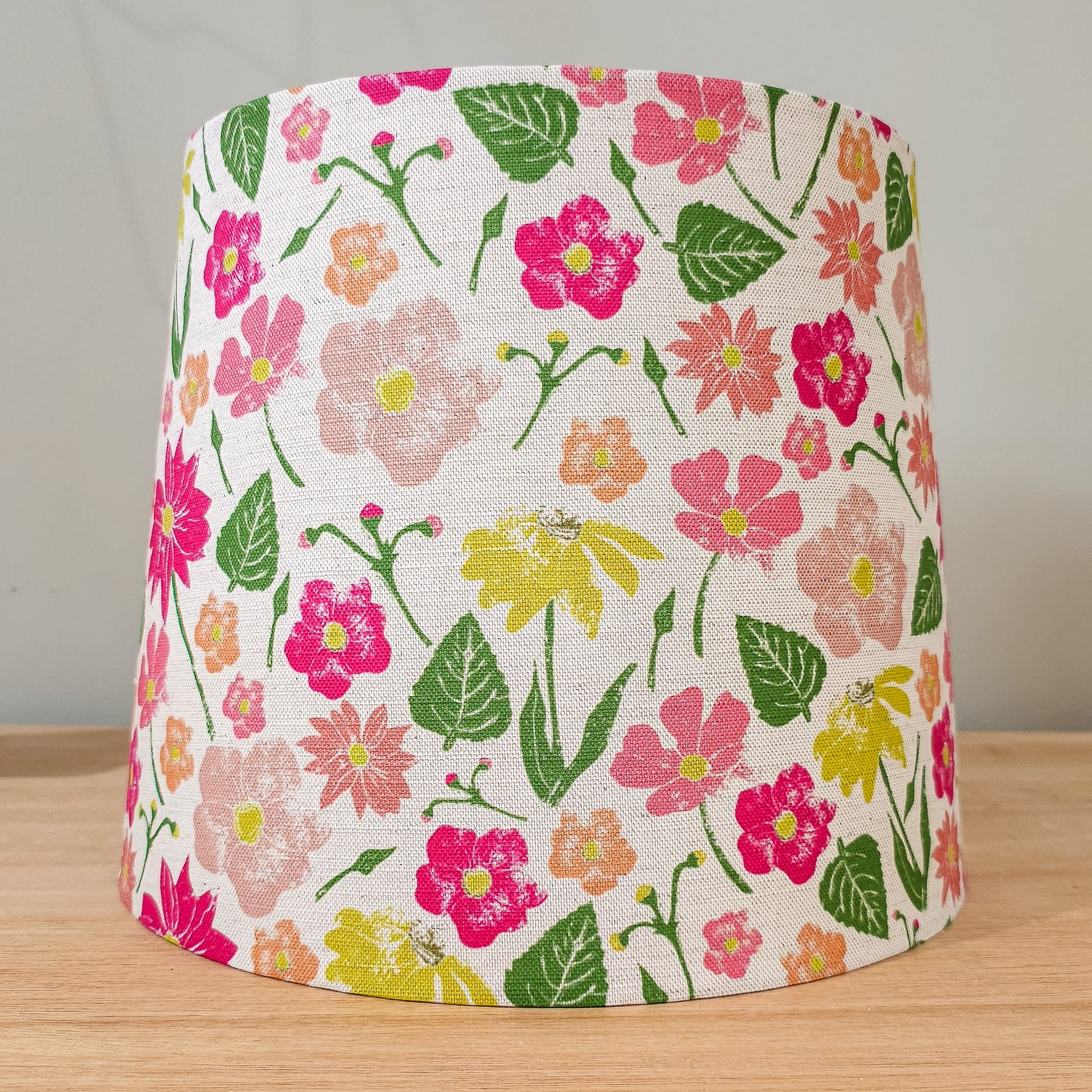 Flower Garden print lampshade by ZIA LIVING, featuring a colourful floral pattern in pink, yellow and red on a white cotton‑linen shade, styled on a wooden surface and neutral wall.