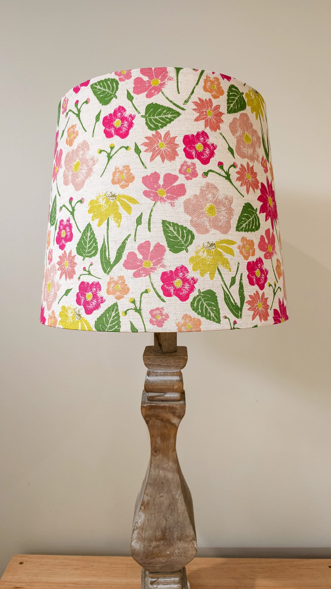 Flower Garden print lampshade by ZIA LIVING, featuring a colourful floral pattern in pink, yellow and red on a white cotton‑linen shade, styled on a wooden lamp base against a neutral wall.