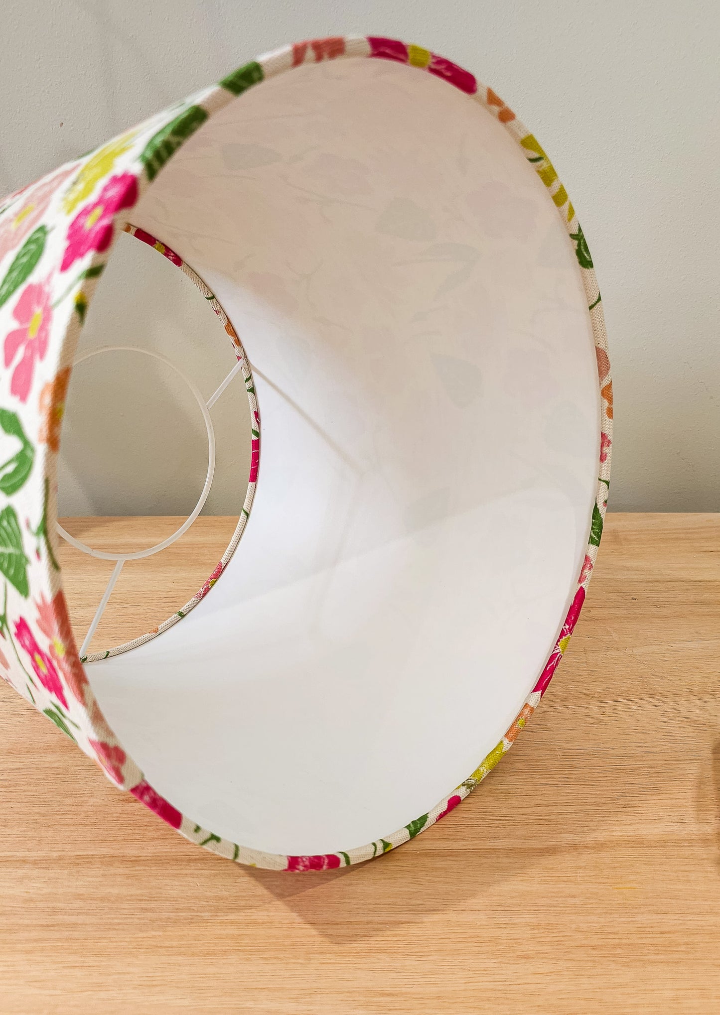 Flower Garden print lampshade by ZIA LIVING, featuring a colourful floral pattern in pink, yellow and red on a white cotton‑linen shade, styled on a wooden surface showing a side view