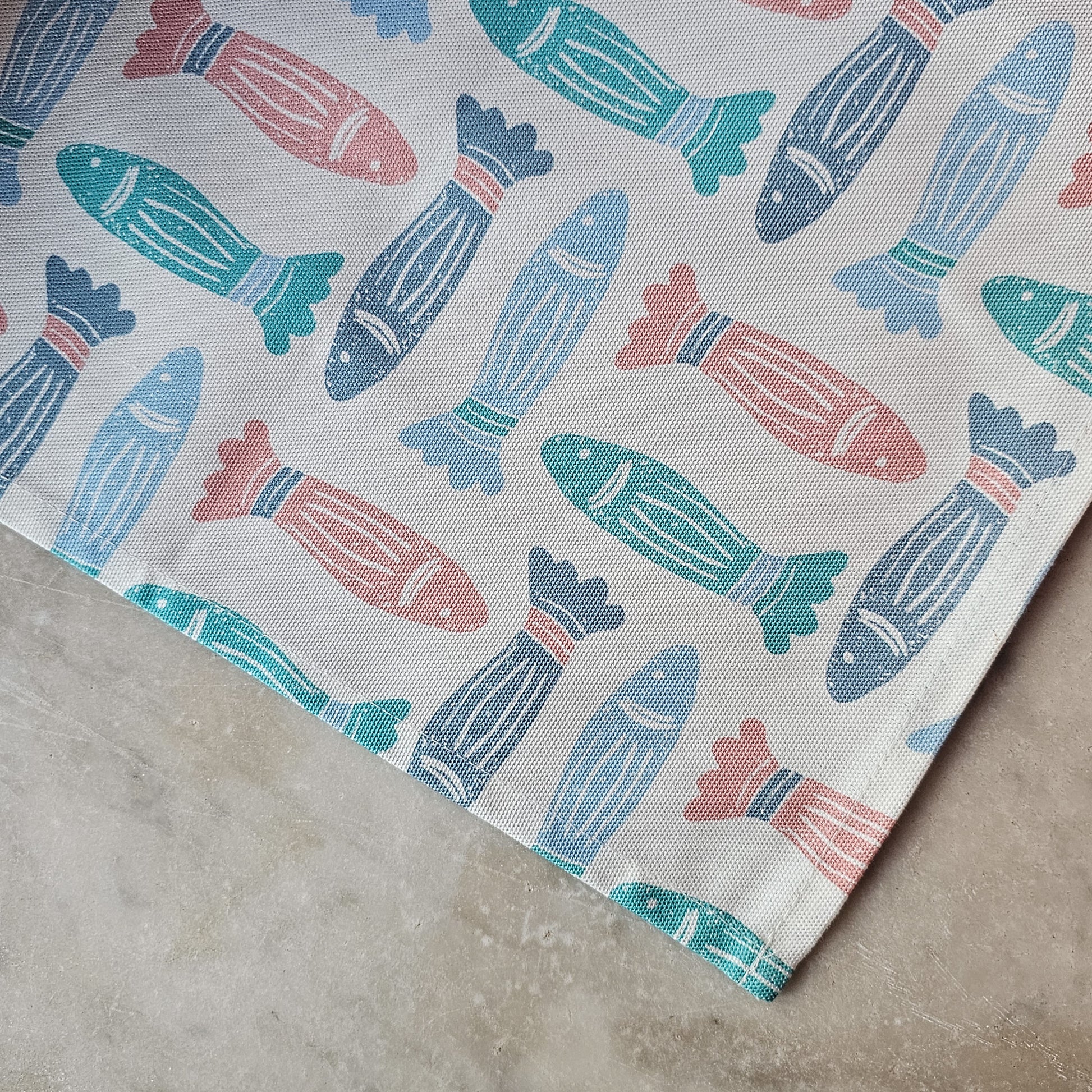 A blue, coral, and green fish‑print tea towel from ZIA LIVING close up on marble kitchen worktop