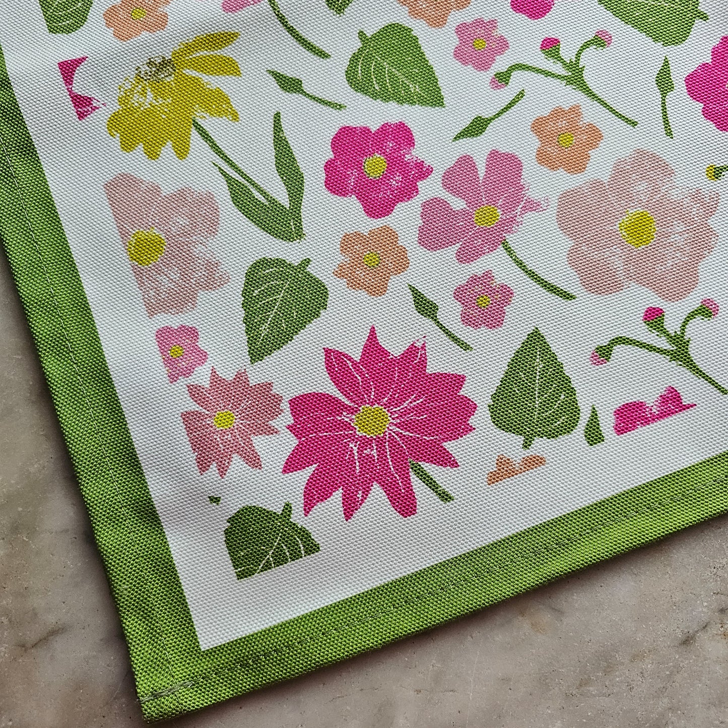 A Flower Garden print cotton tea towel close up from ZIA LIVING arranged on a white marble surface
