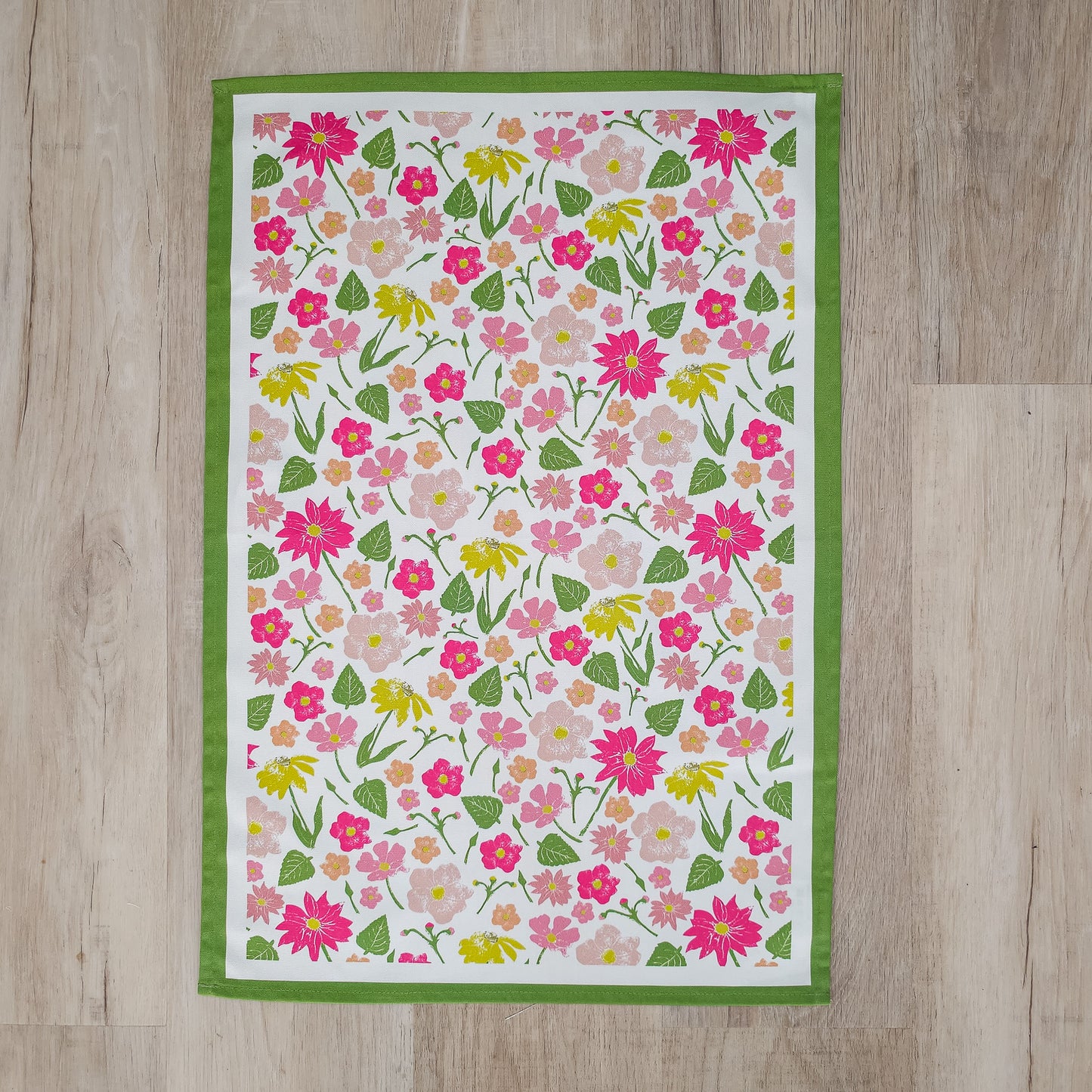 A Flower Garden print colourful tea towel from ZIA LIVING arranged on flat showing full design on a wooden surface.