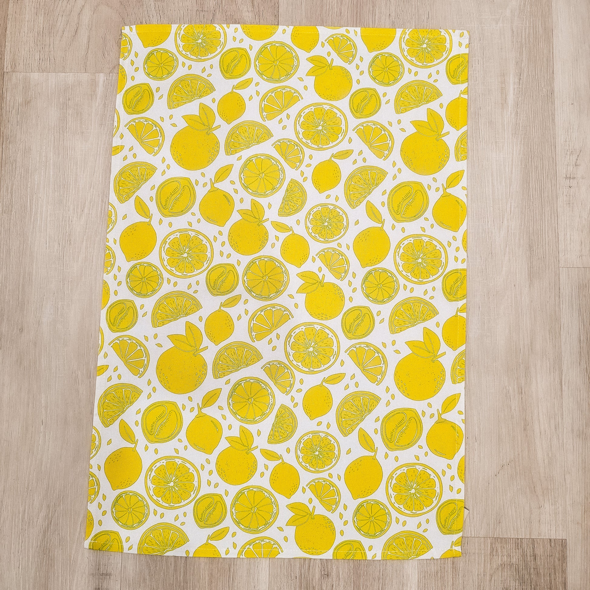 Lemon patterned tea towel flat showing full design on wooden background— ZIA LIVING