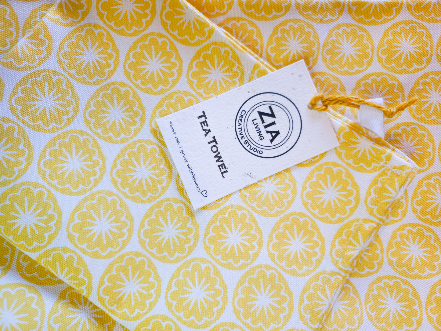 Yellow seedhead  lemon print tea towel  folded with Zia Living wild seed card label
