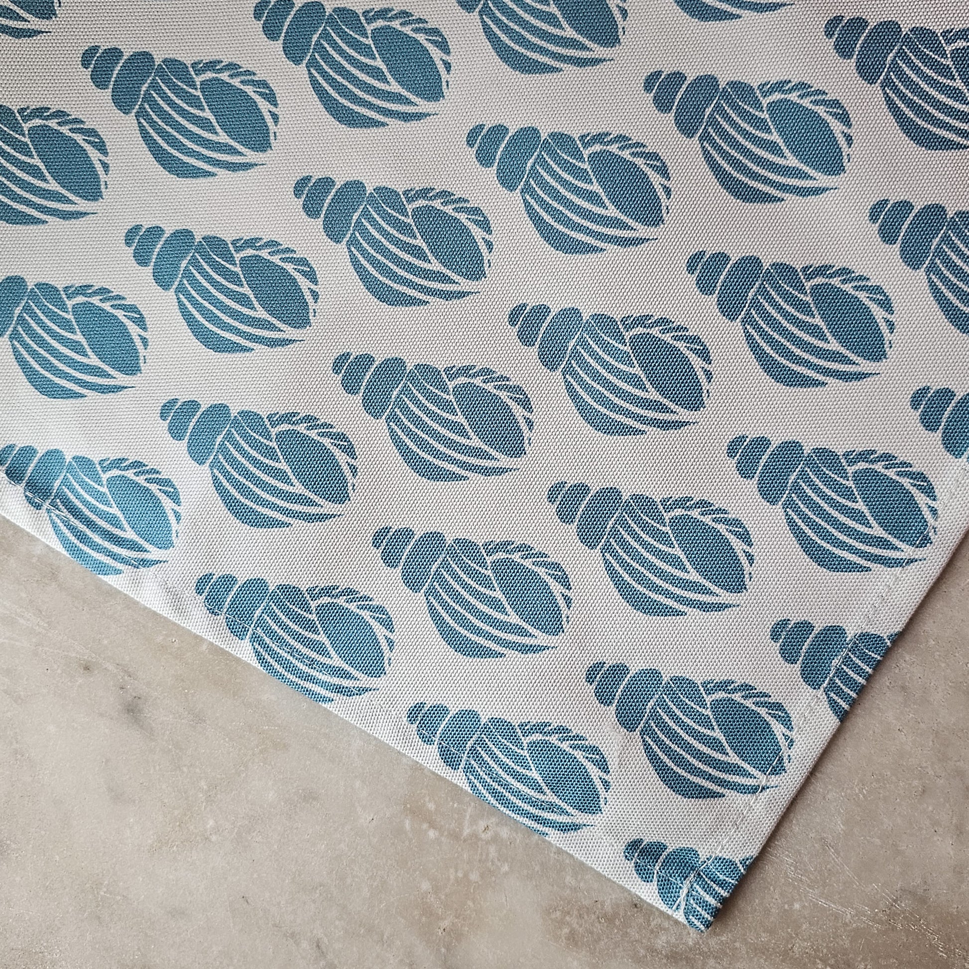 Sea Blue Shell tea towel featuring a repeating hand‑carved shell motif in blue on a white background, photographed close up — ZIA LIVING.