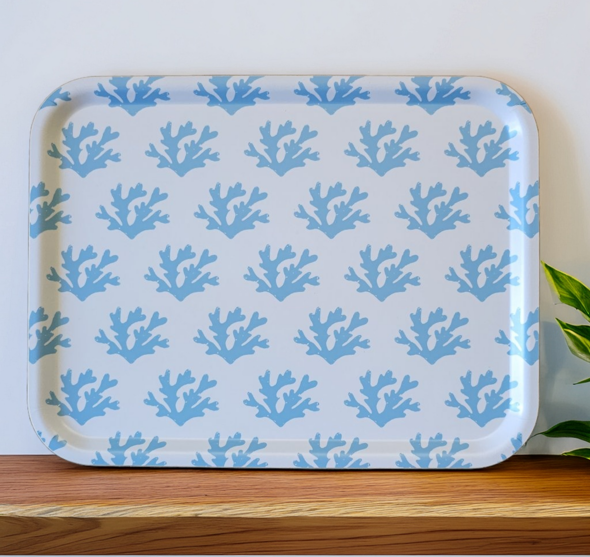 White rectangular tray with a soft blue seaweed coral pattern styled on a wooden surface, finished with a fresh coastal touch from a green plant. ZIA LIVING